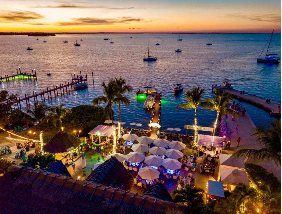 An aerial view of a beach at sunset with boats in the water.