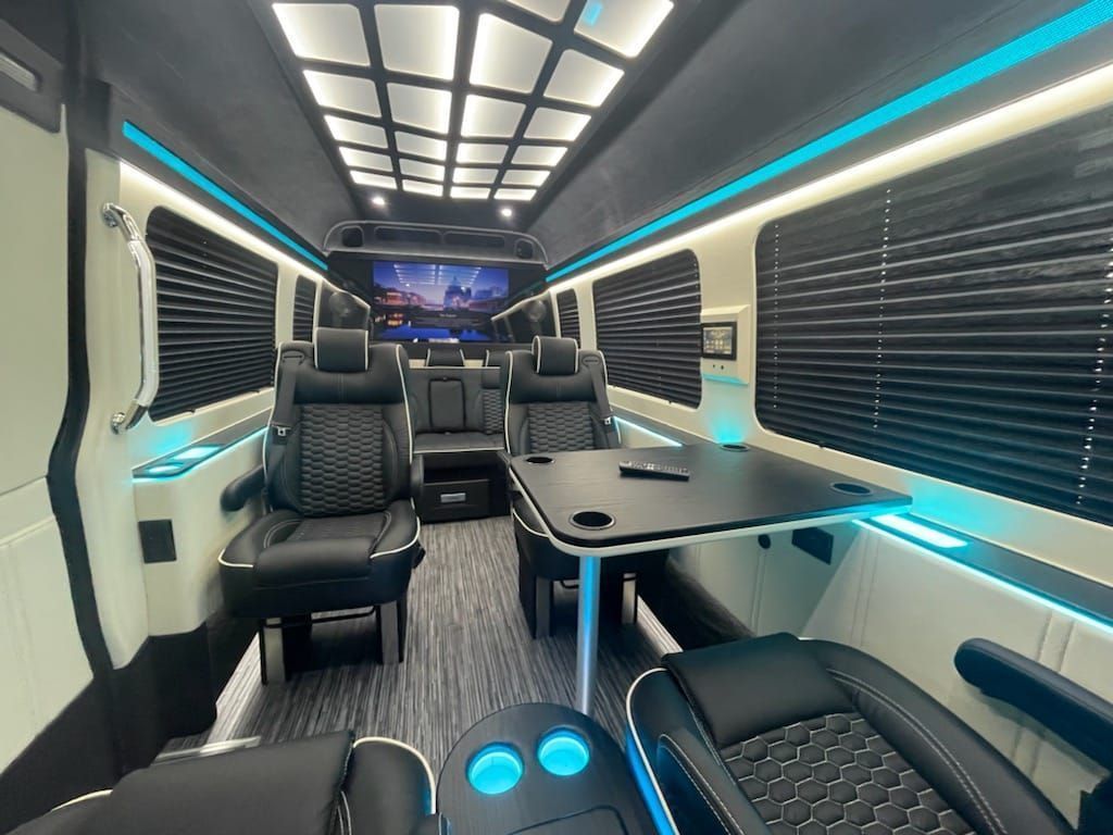 The inside of an executive sprinter with a table and chairs.