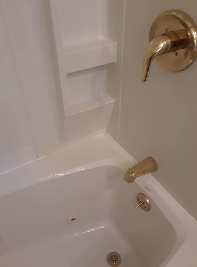 A white bathtub with a gold faucet in a bathroom.
