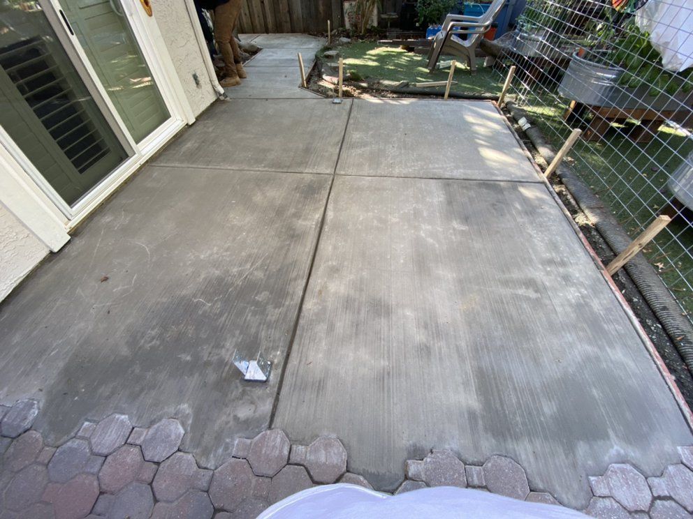 A concrete patio is being built in the backyard of a house.