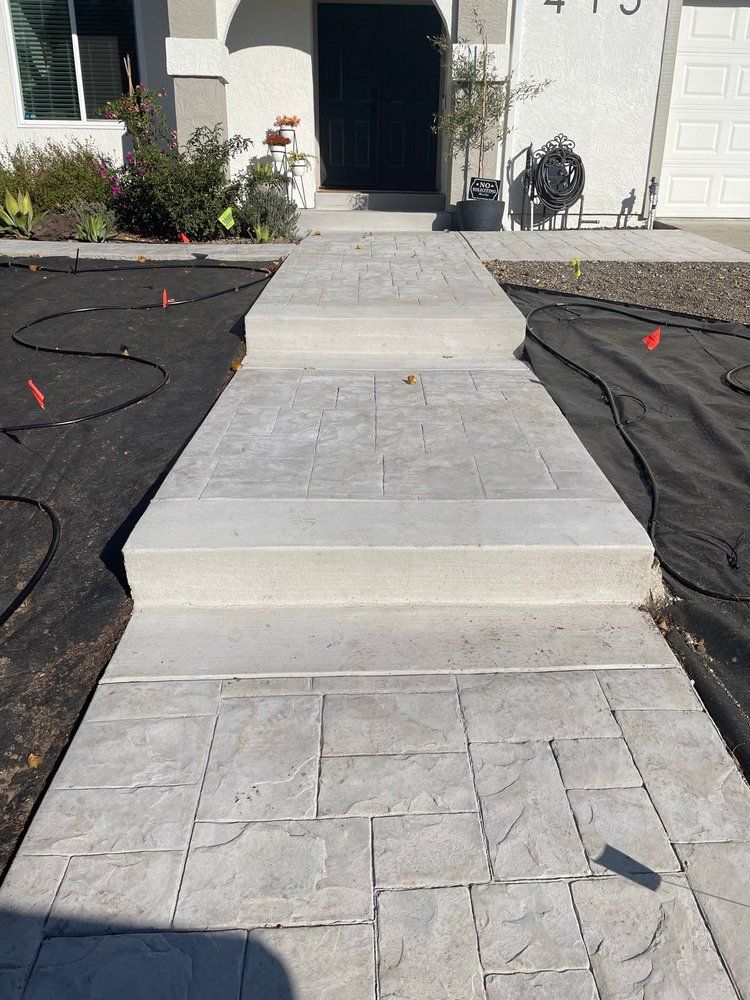 A concrete walkway leading to the front door of a house.