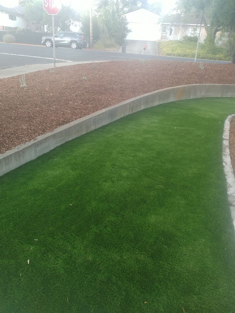 A lush green lawn with a stop sign in the background.