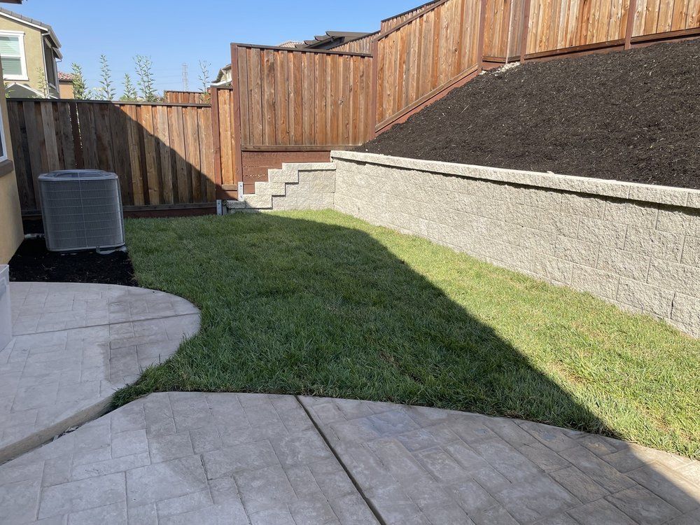 A backyard with a concrete patio and a wooden fence