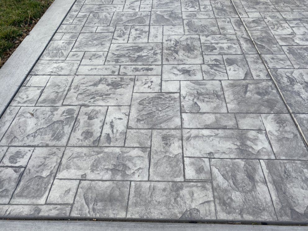A close up of a concrete walkway with a brick pattern.