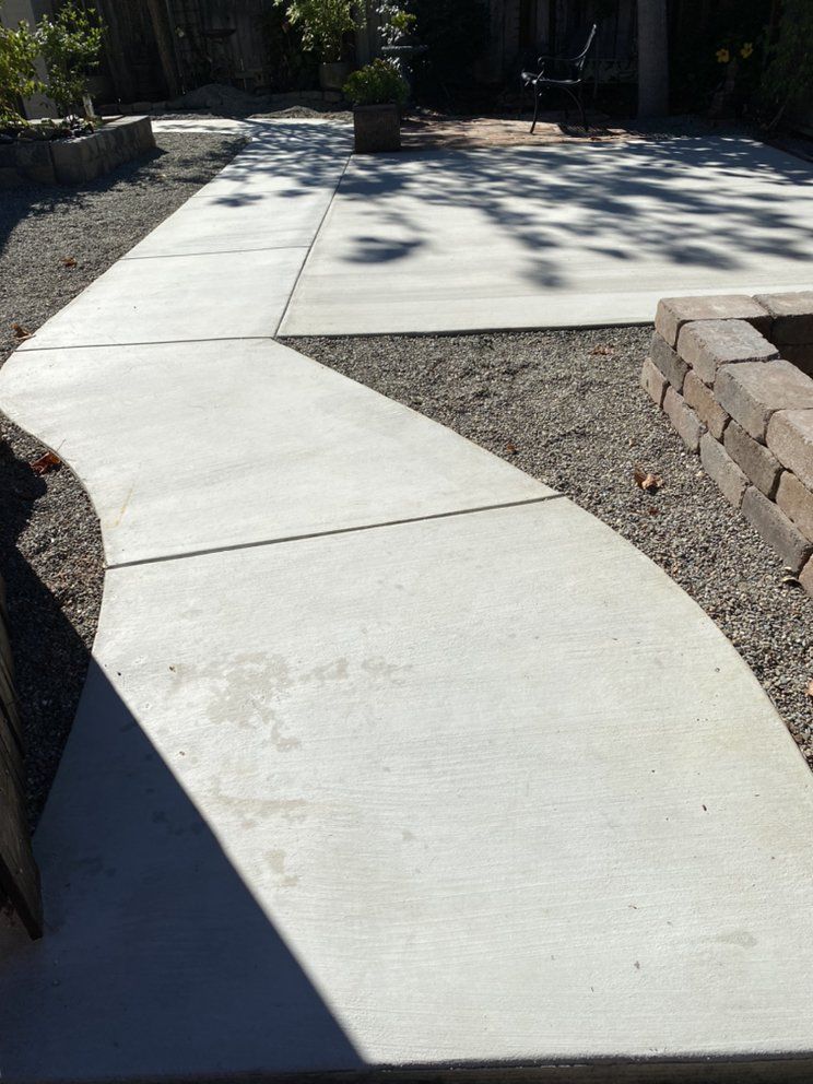 A concrete walkway leading to a patio and a fire pit