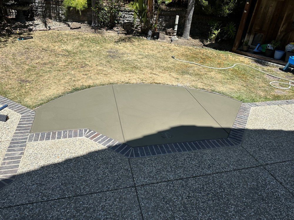 A concrete driveway with a brick border and a grassy area in the background.