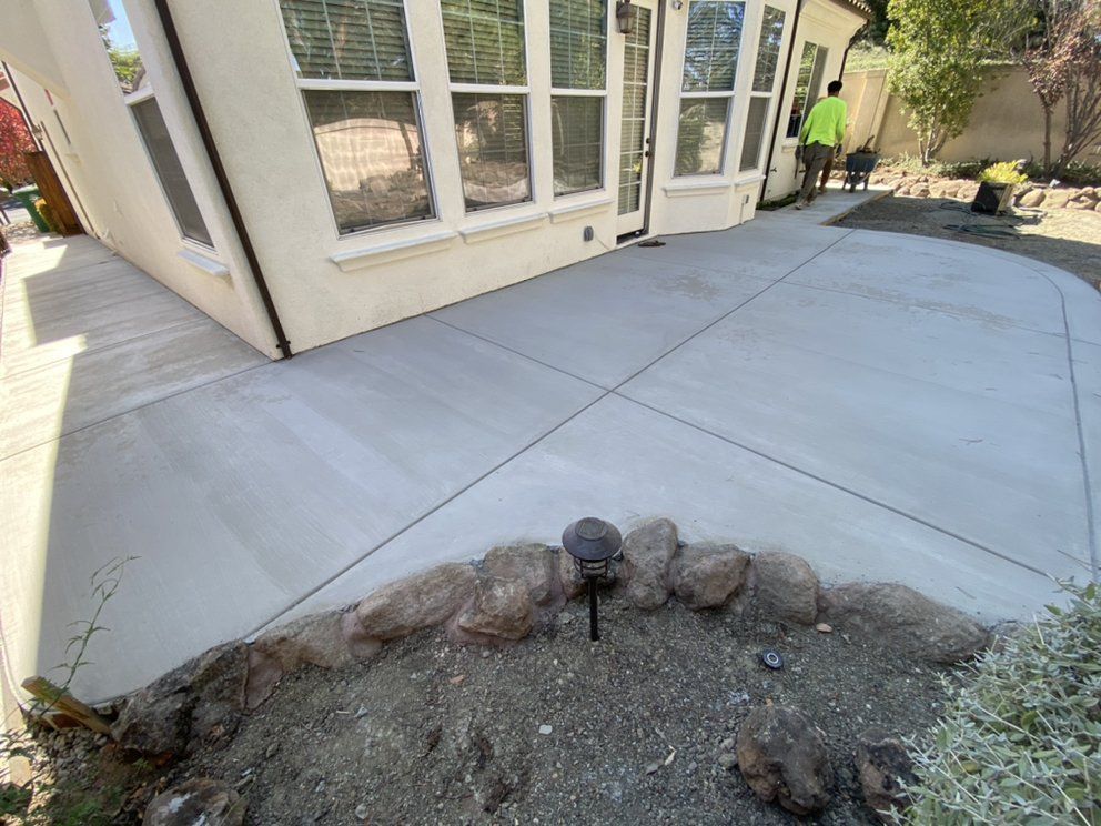 A man is standing on a concrete patio in front of a house.
