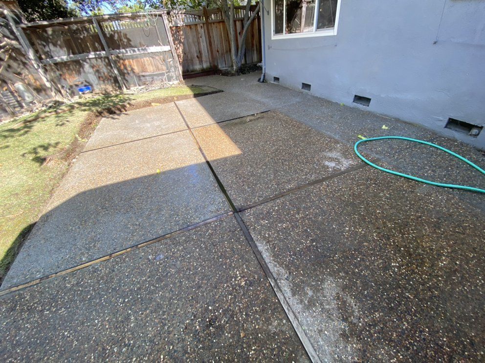 A concrete patio with a green hose next to it.