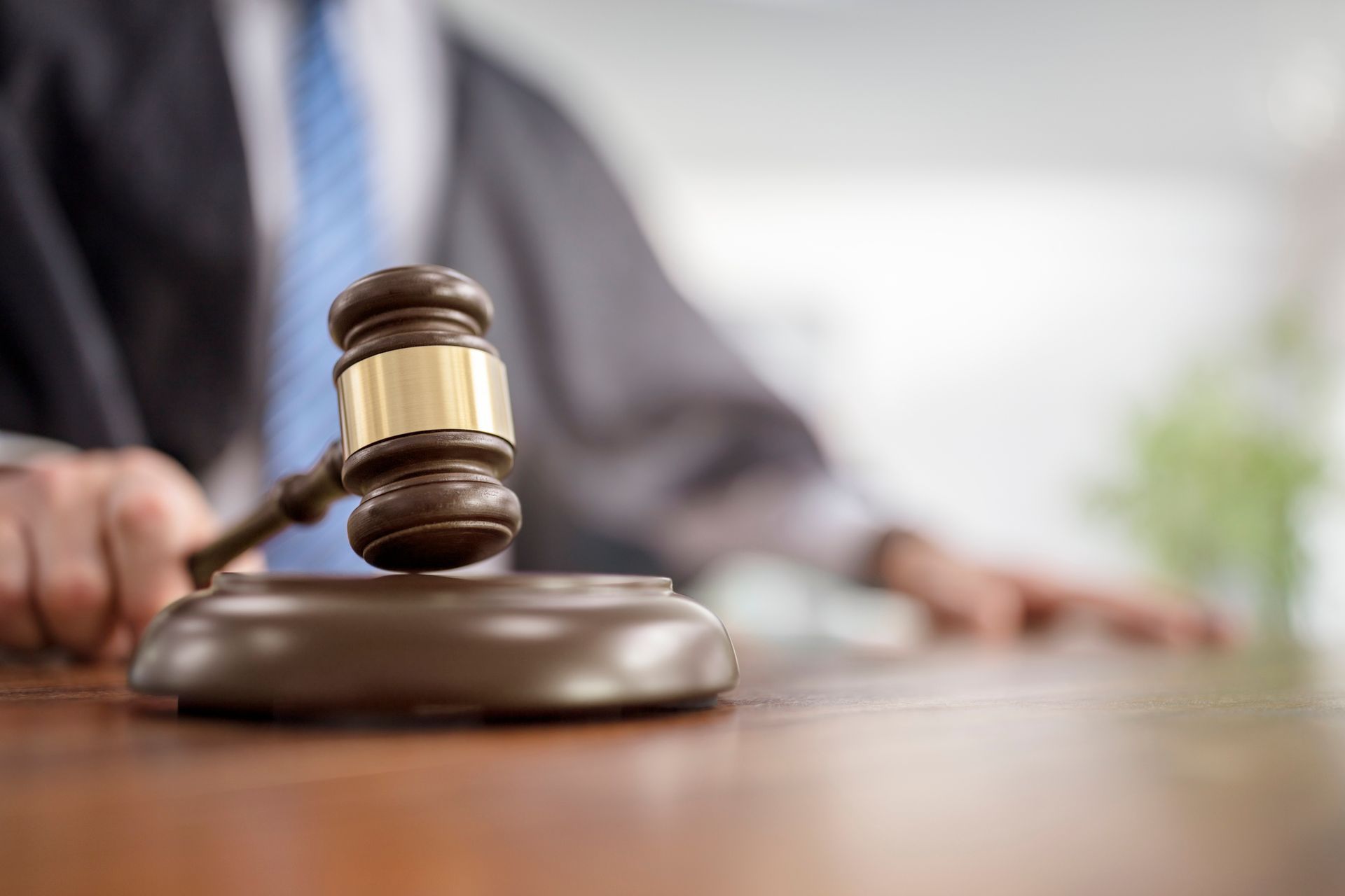 Gavel on a wooden block; judge in the background.