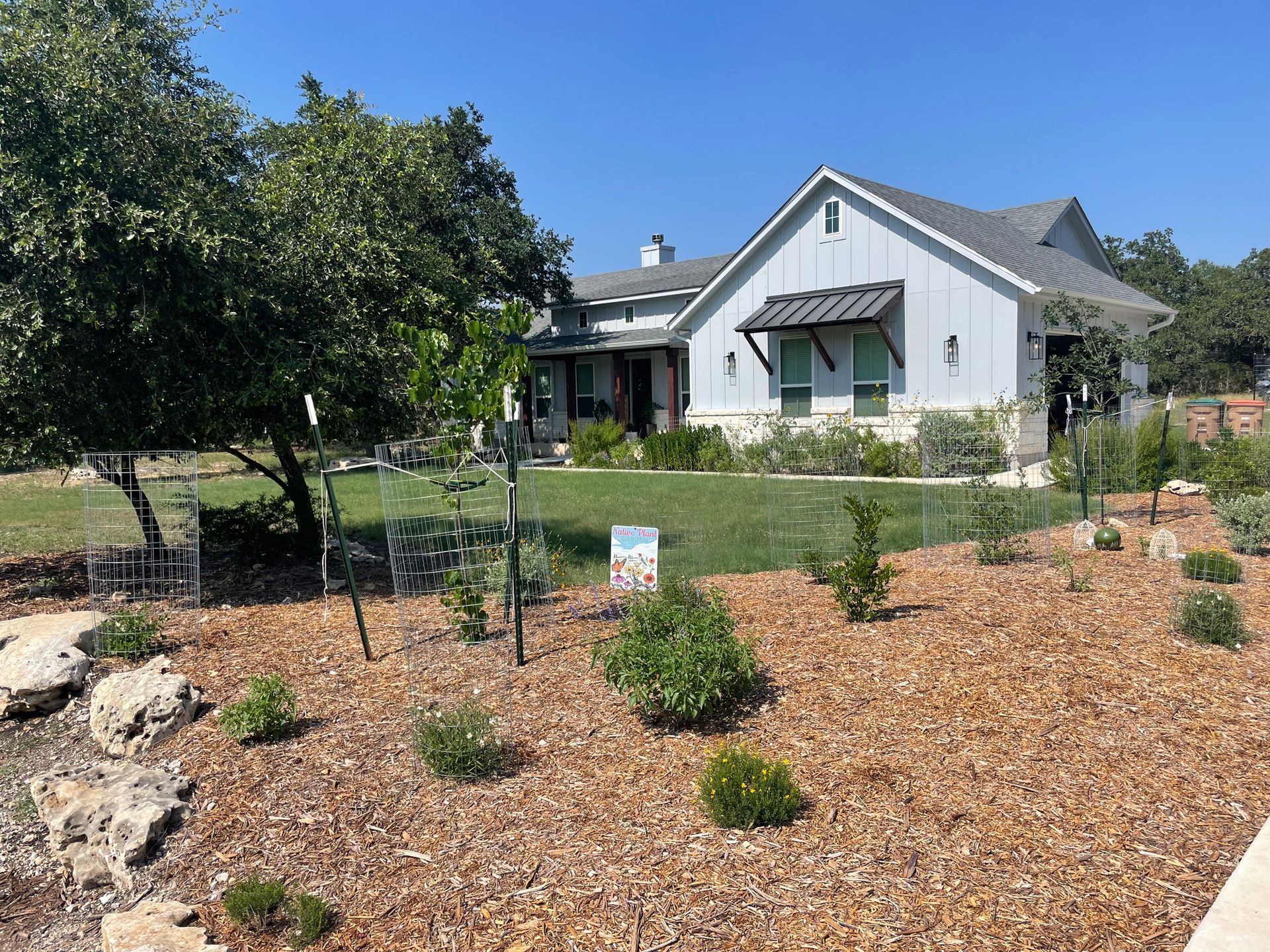 A large white house with a lot of plants in front of it.