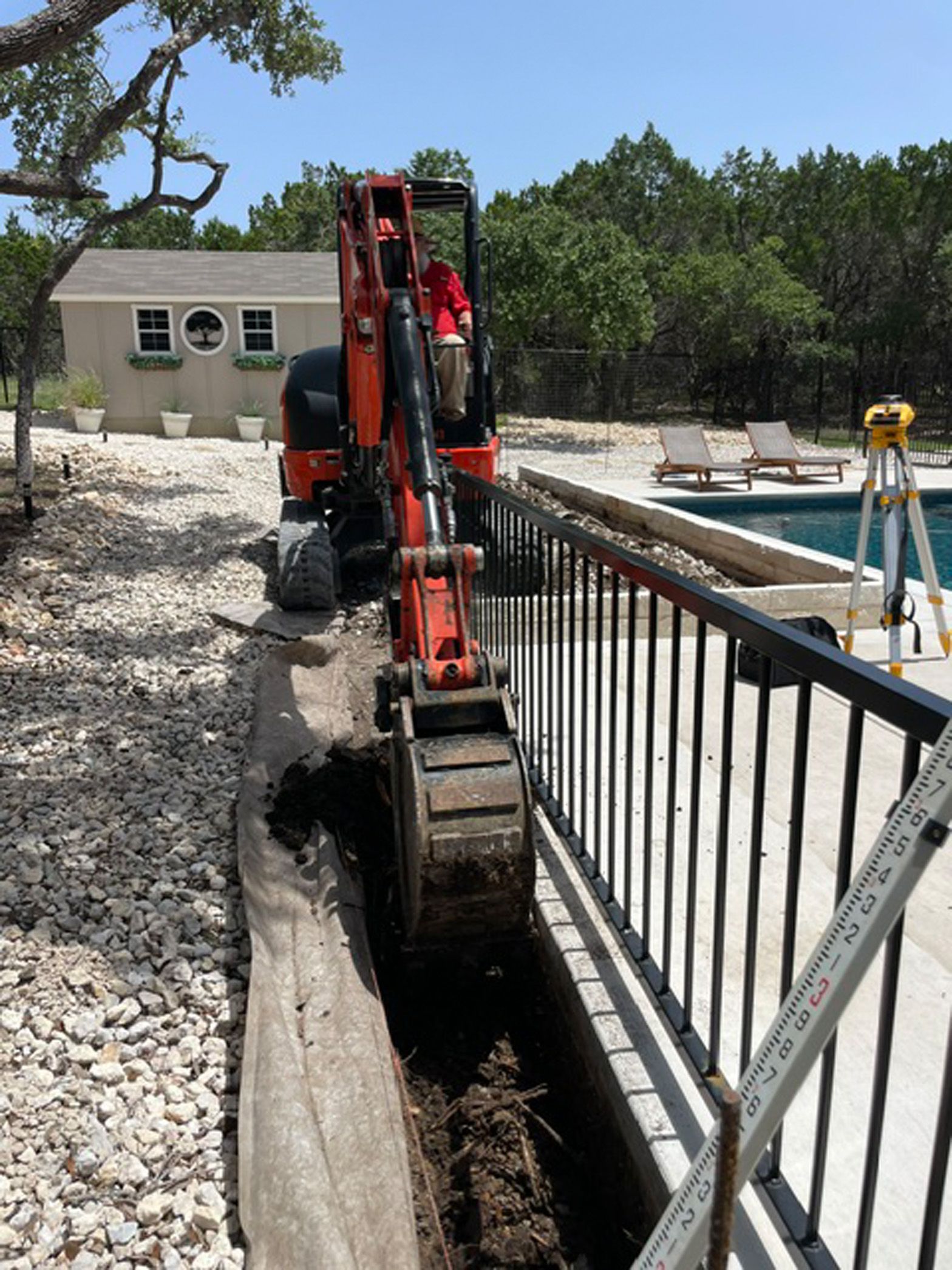 A man is driving a small excavator in a backyard.