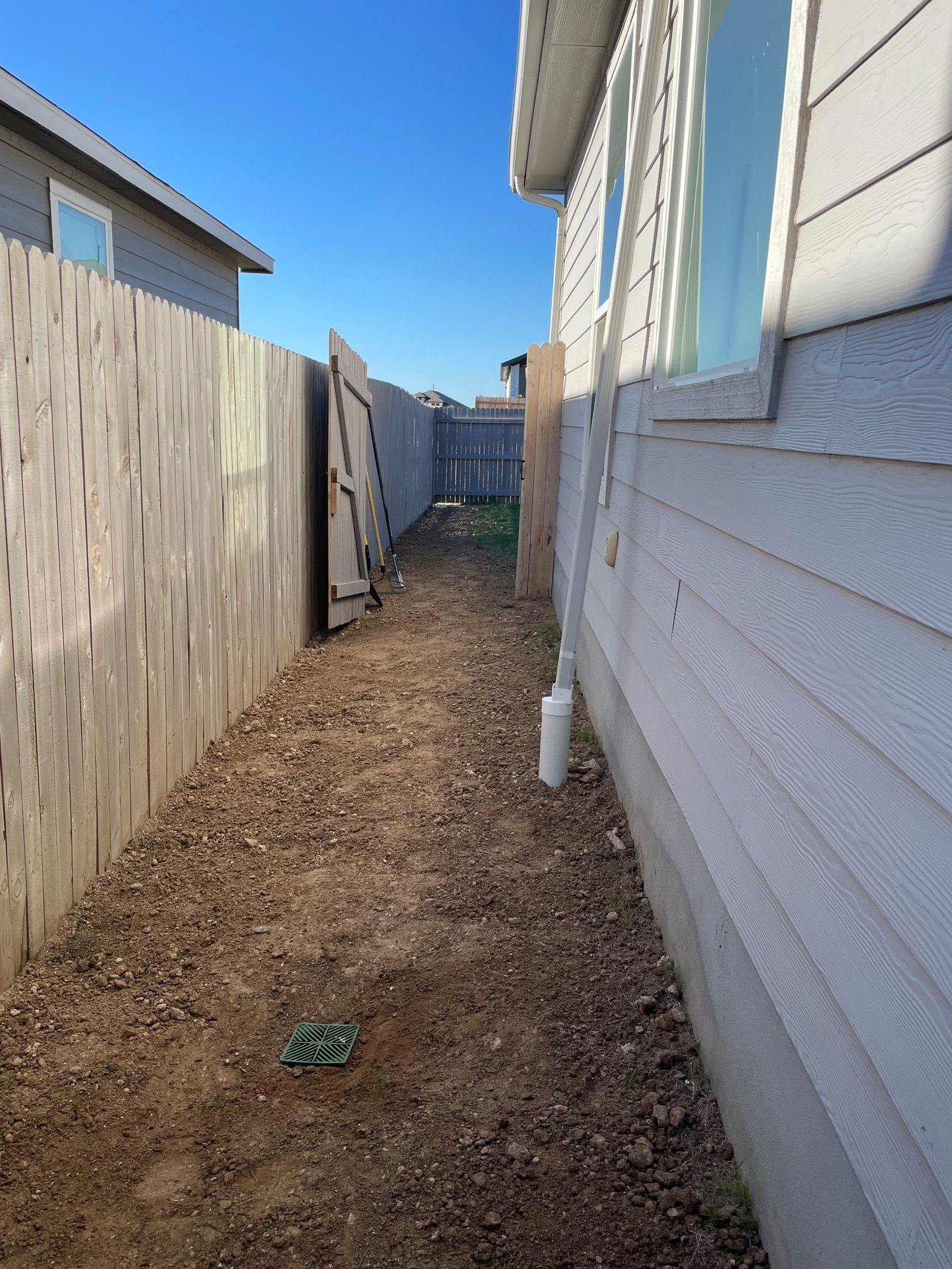 A dirt path leading to a house with a wooden fence.