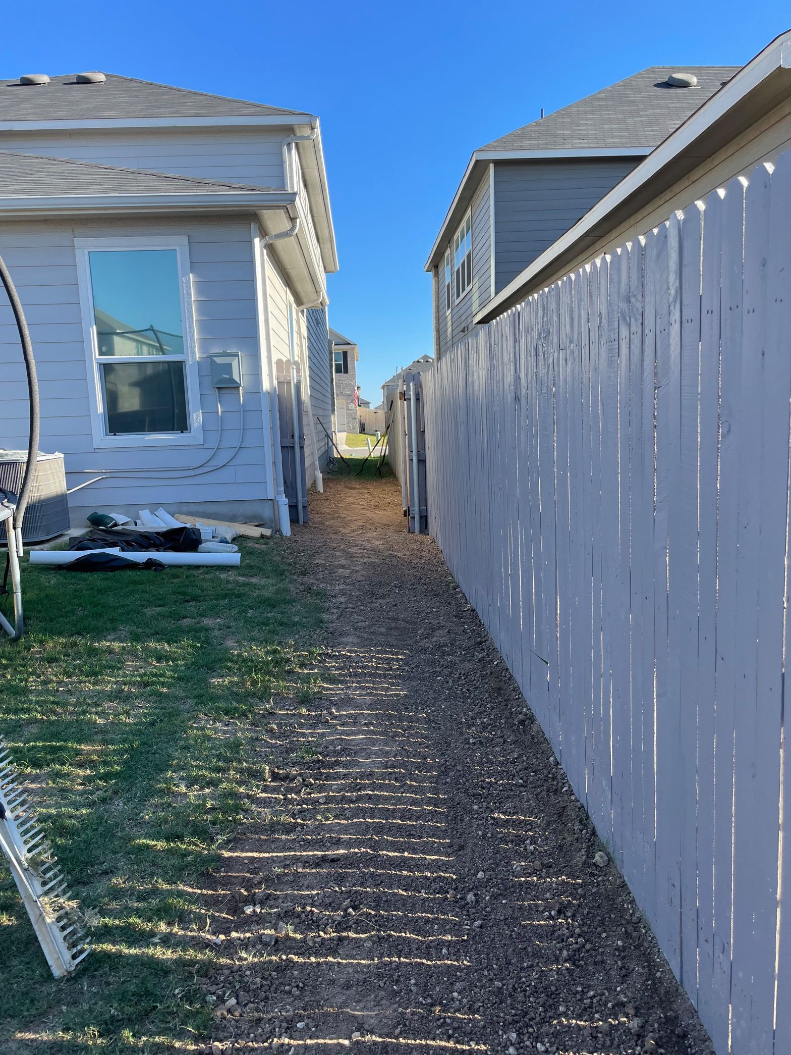 There is a white fence between two houses.