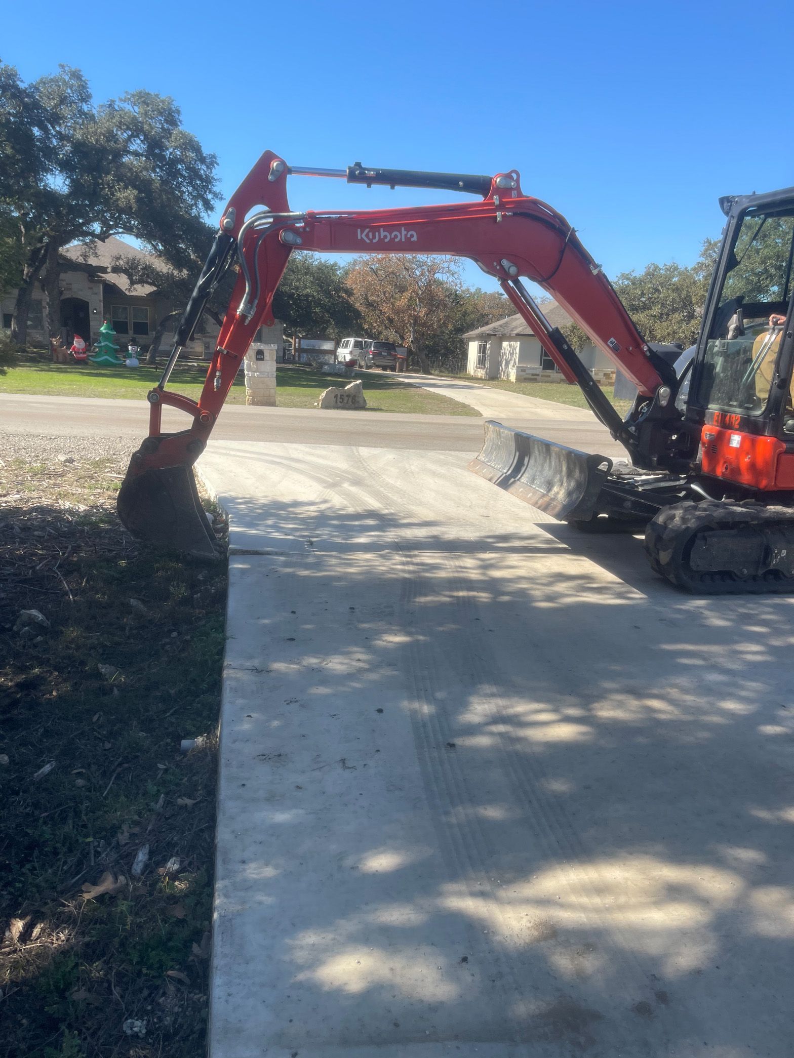 A red and black excavator is parked on the side of the road.