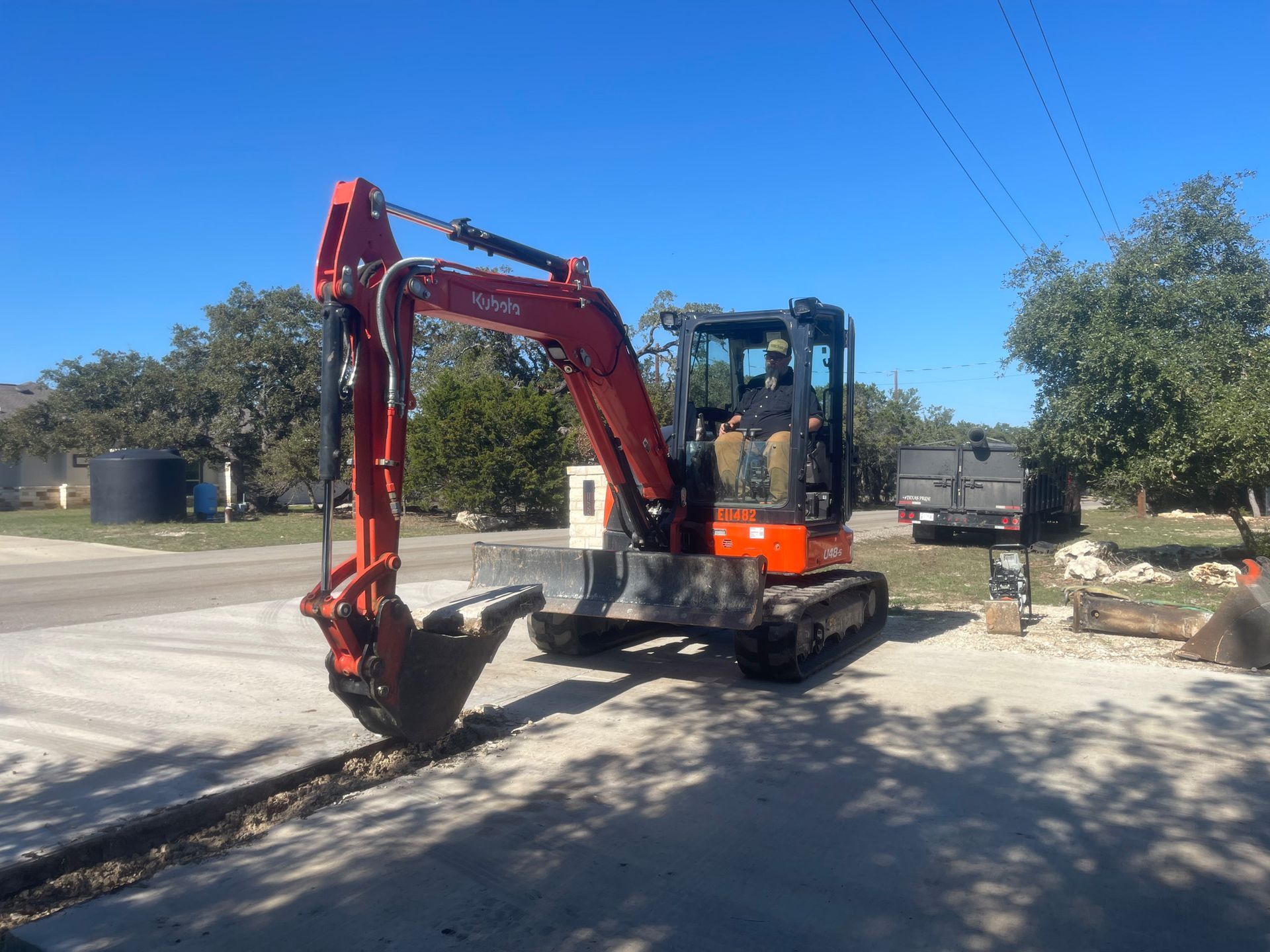 A red and orange excavator is parked on the side of the road.