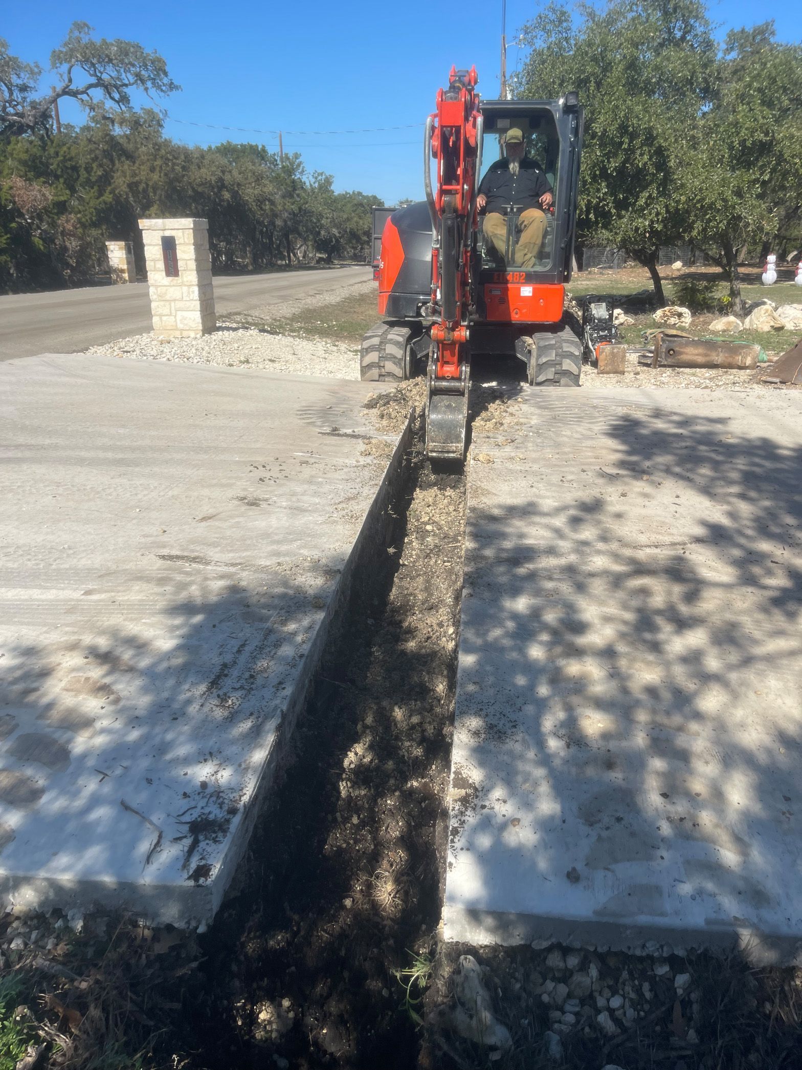 A red and black excavator is digging a hole in the ground.