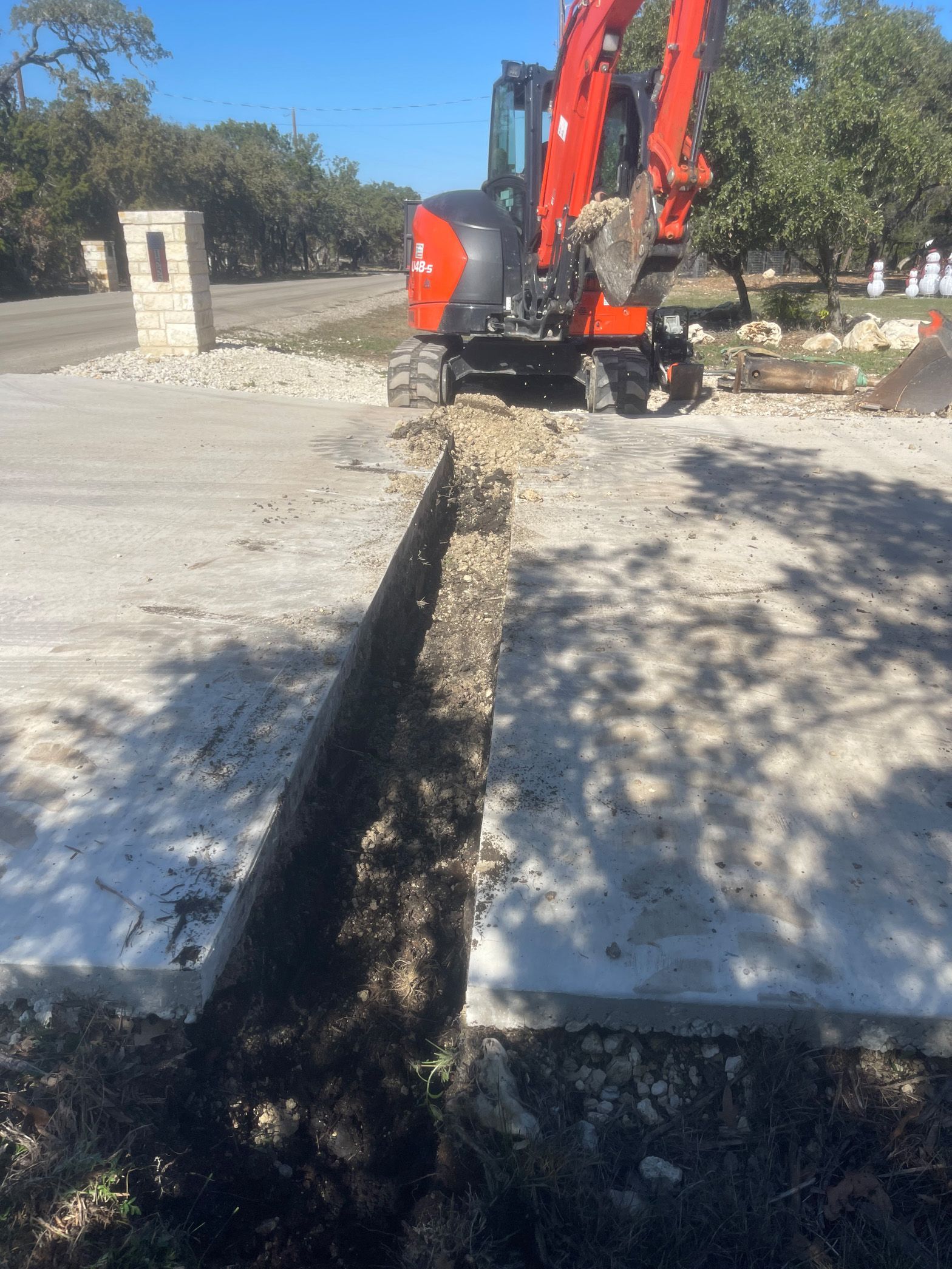 A red and black excavator is digging a hole in the ground.