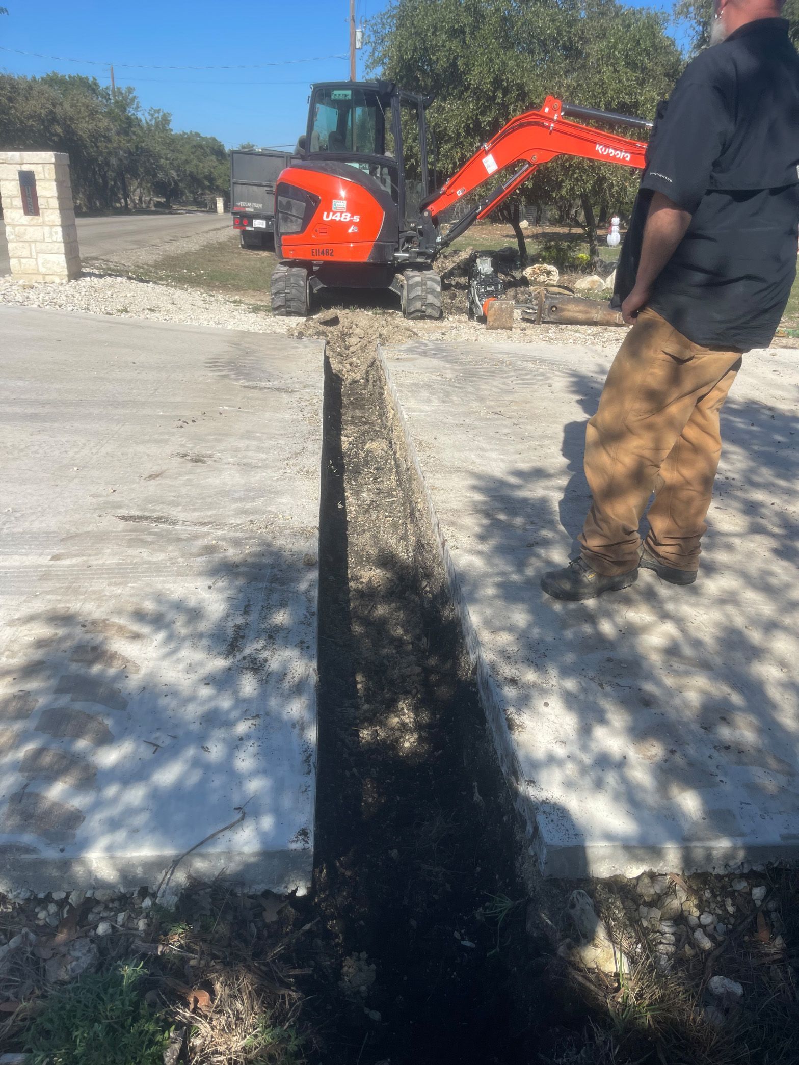A man is standing in front of a red excavator.