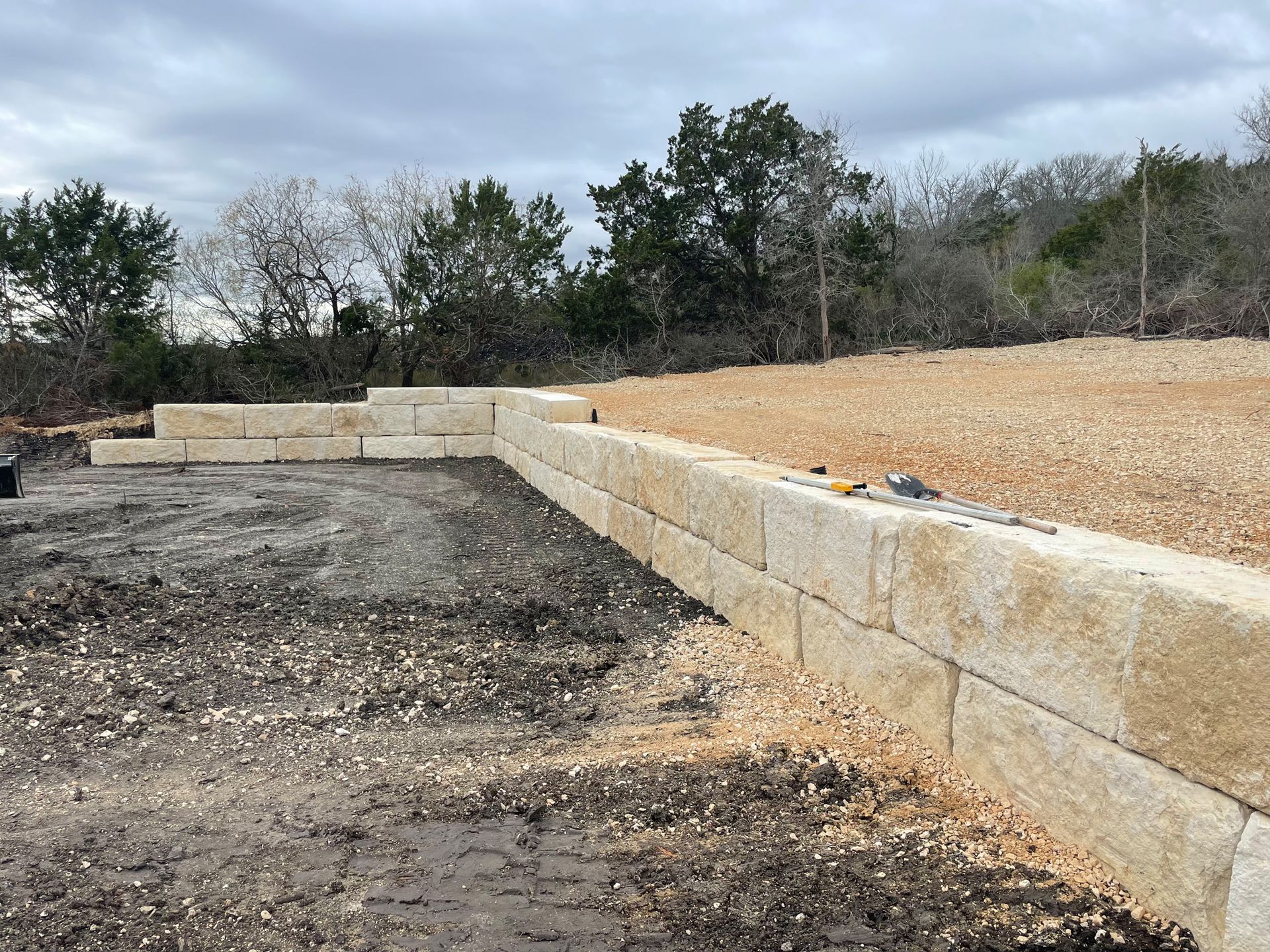 A stone wall is being built in the middle of a dirt field.