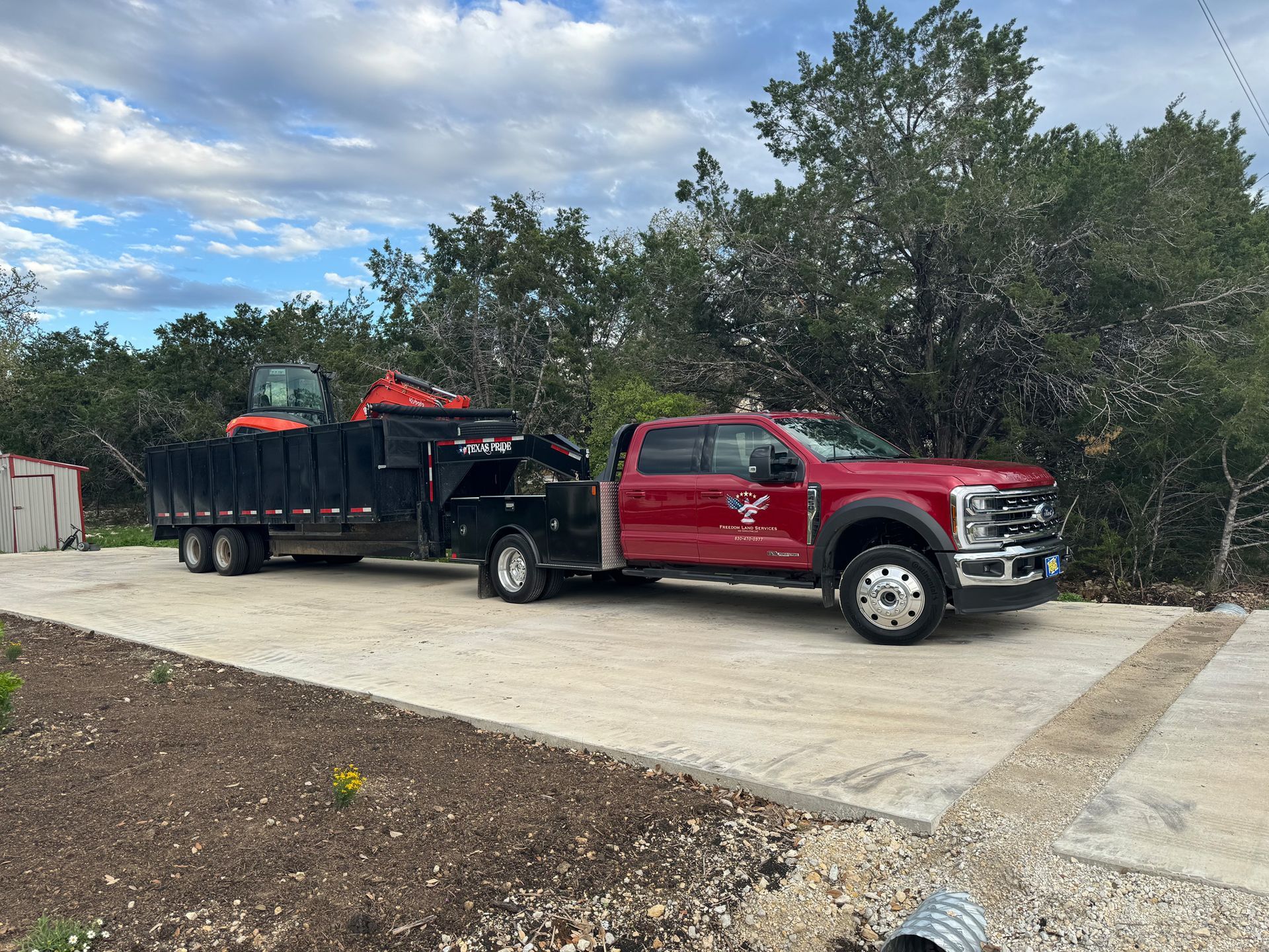 A red truck with a trailer attached to it is parked in a driveway.
