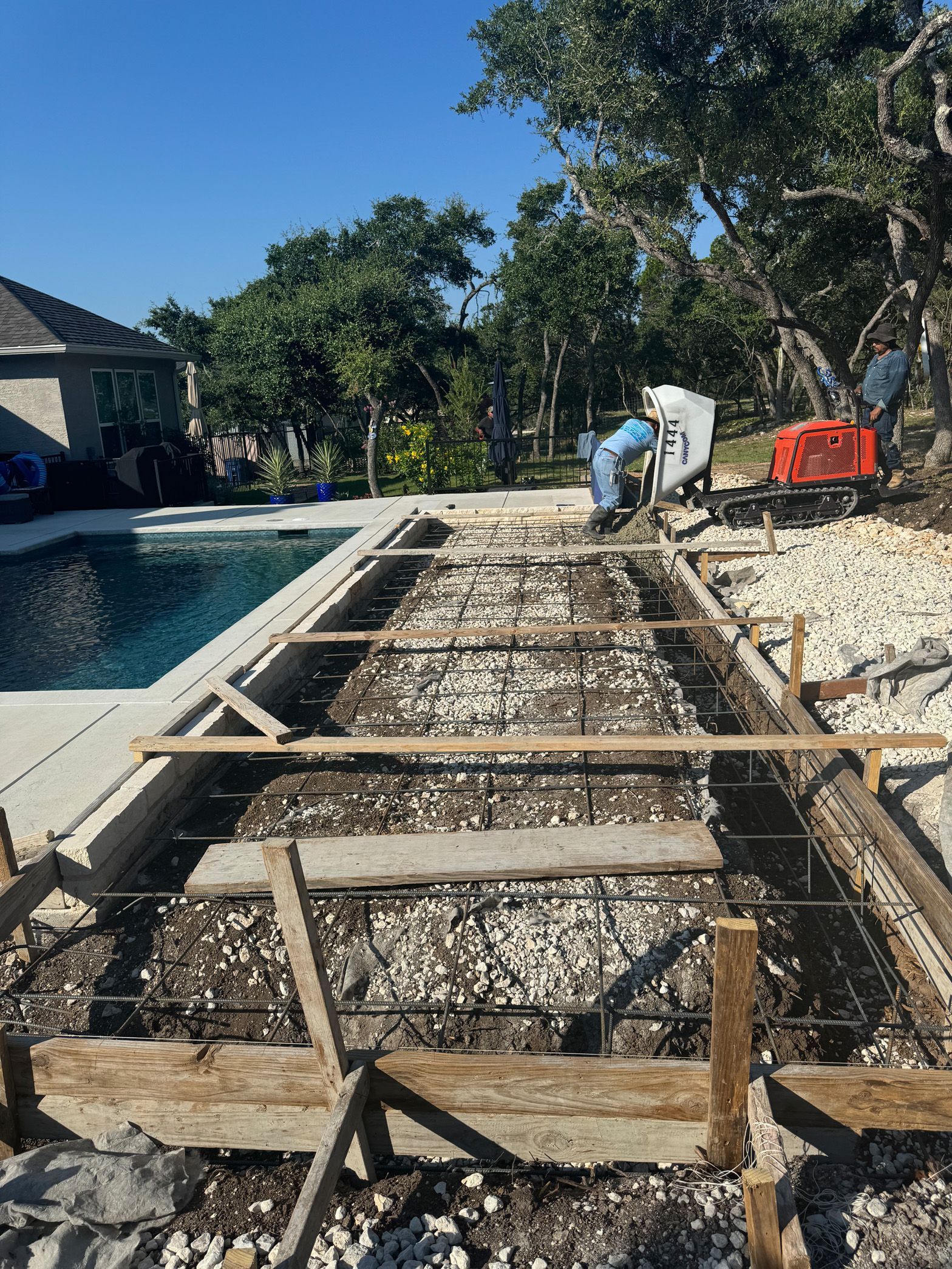 A swimming pool is being built in the backyard of a house.