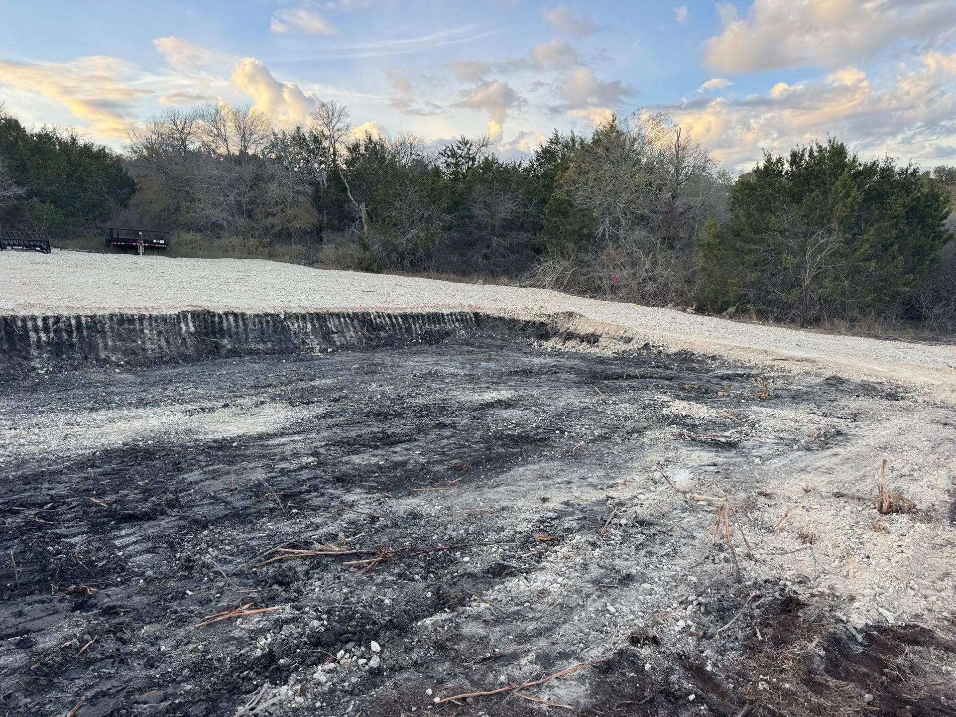 A field with a lot of dirt and trees in the background.