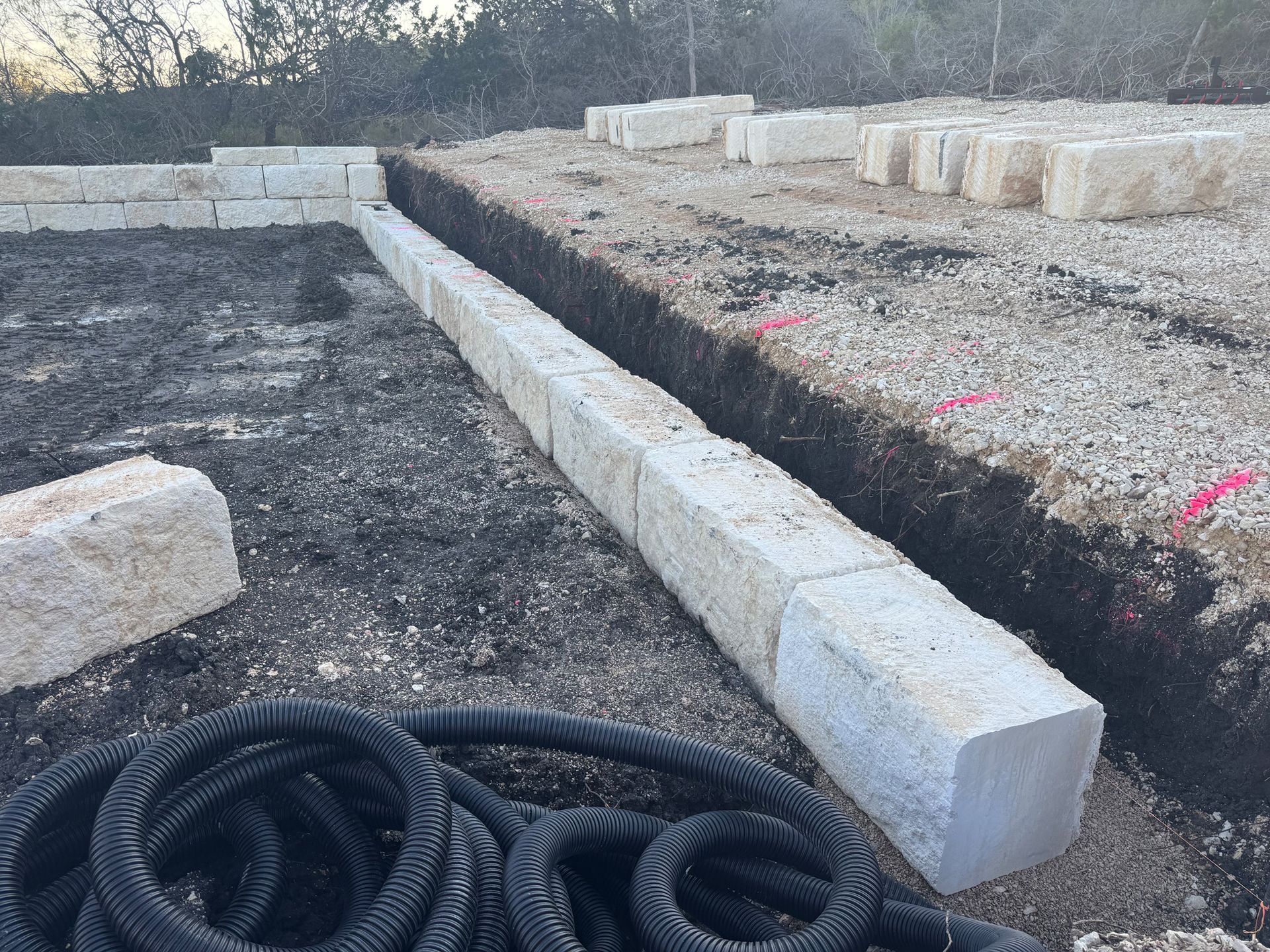 A hose is laying on the ground next to a pile of concrete blocks.