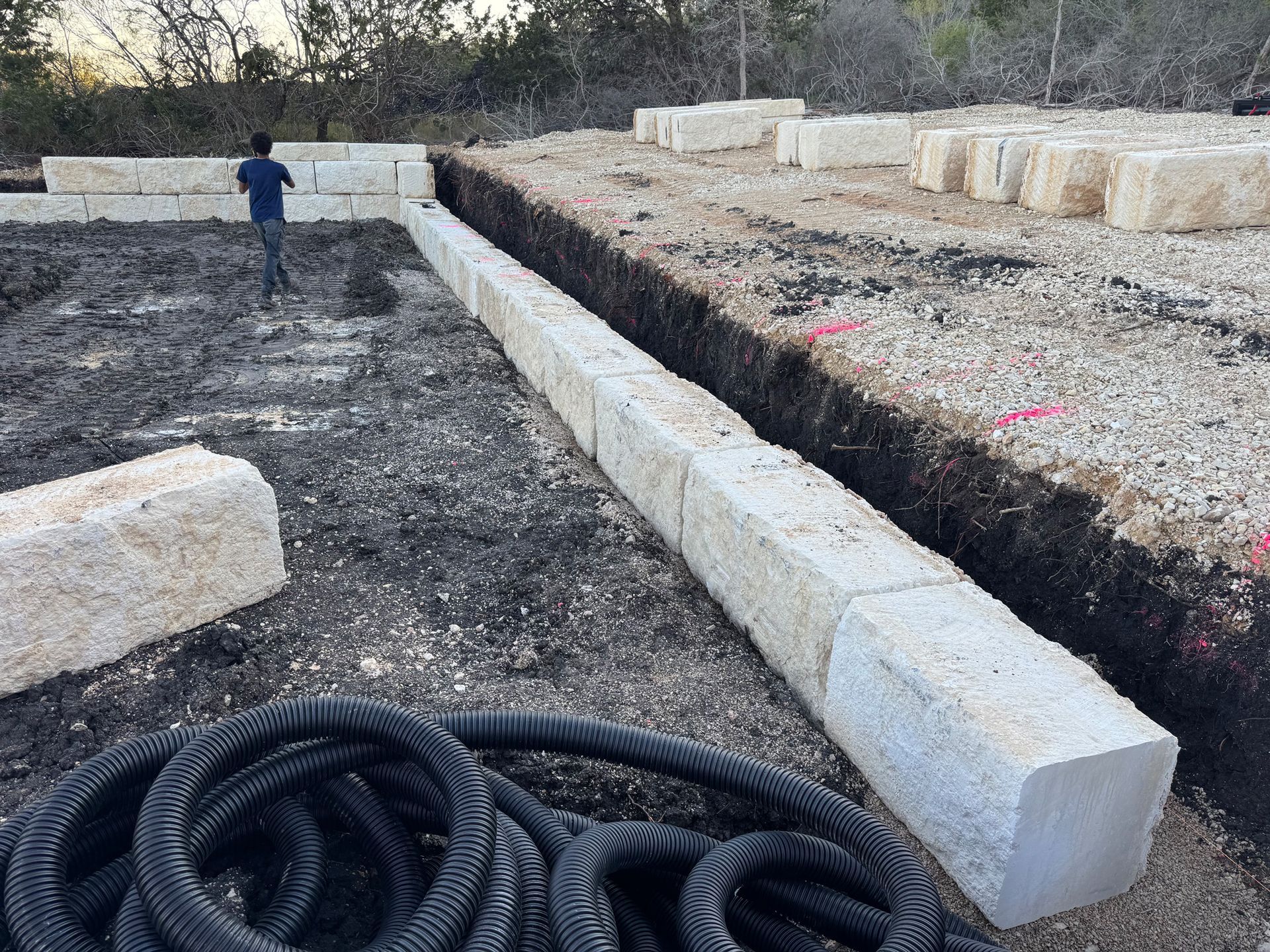 A man is standing in a dirt field next to a hose.
