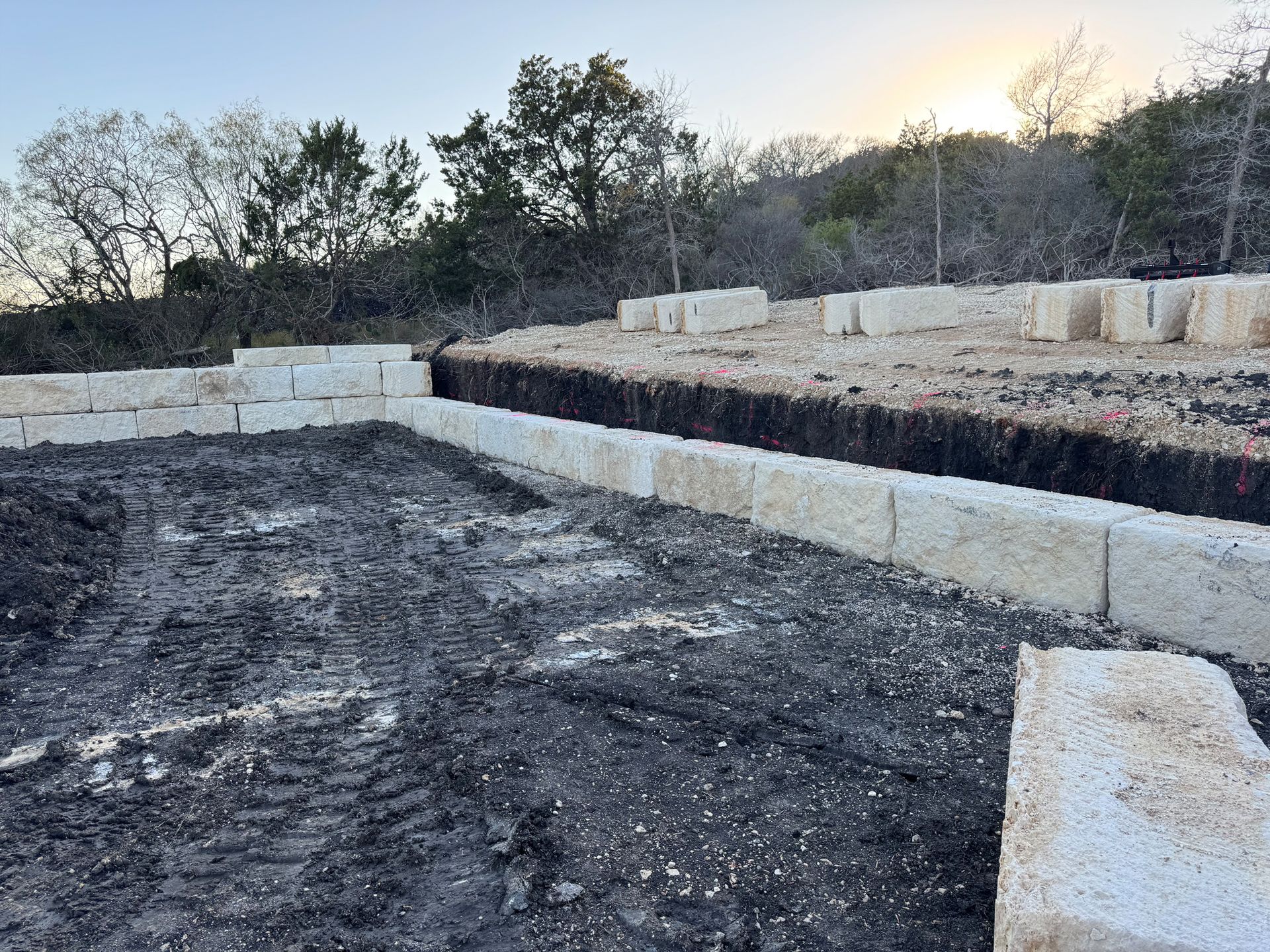 A brick wall is being built on top of a dirt field.