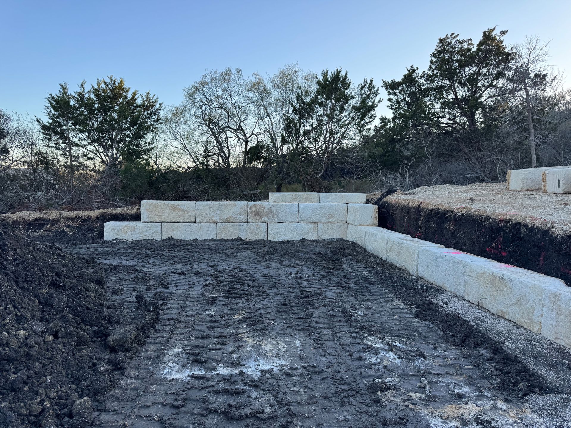 A construction site with a lot of concrete blocks and trees in the background.