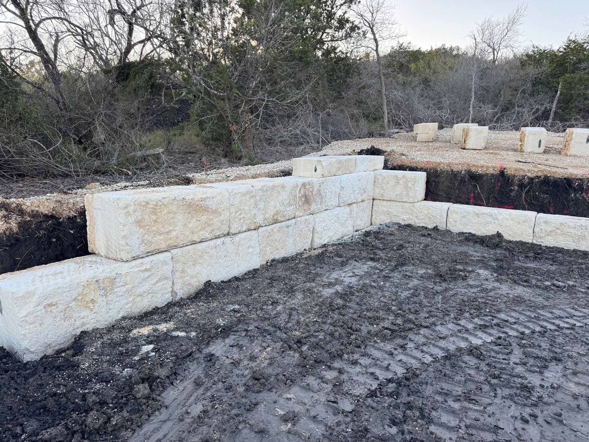 A concrete wall is being built in the middle of a dirt field.