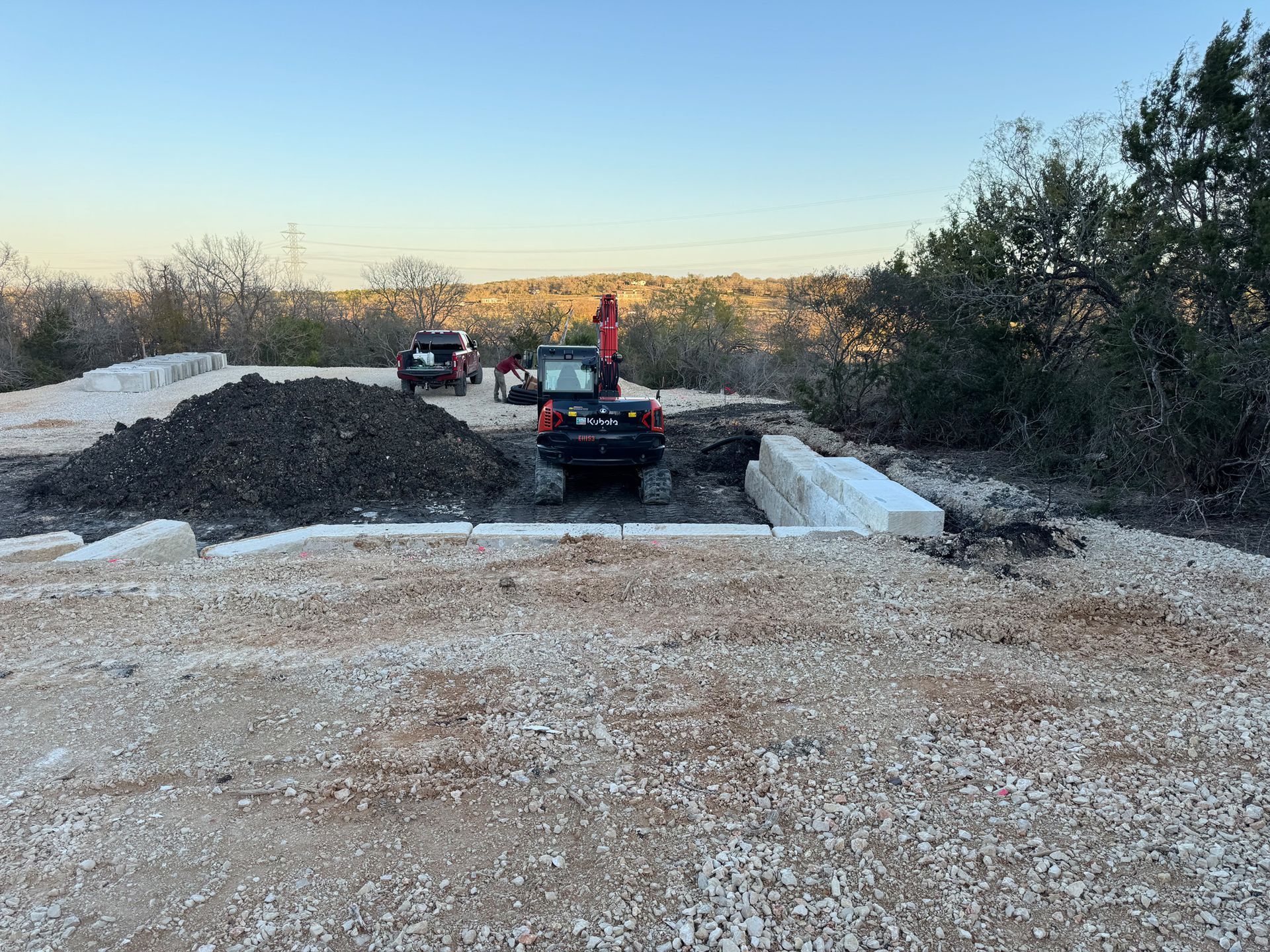 A jeep is driving down a dirt road next to a pile of dirt.
