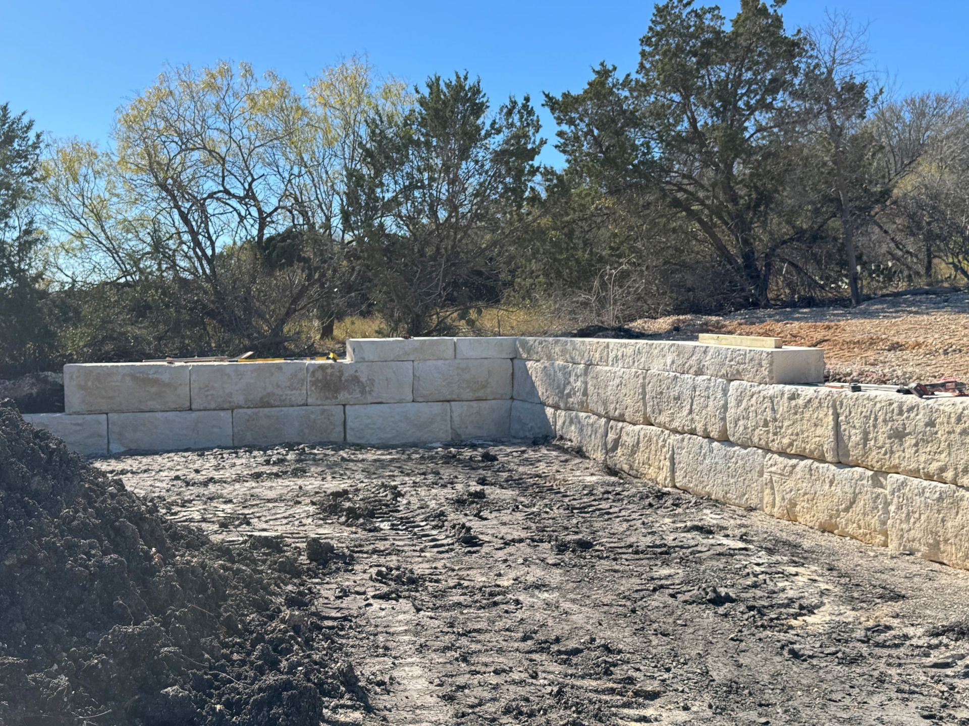 A stone wall is being built in the middle of a dirt field.
