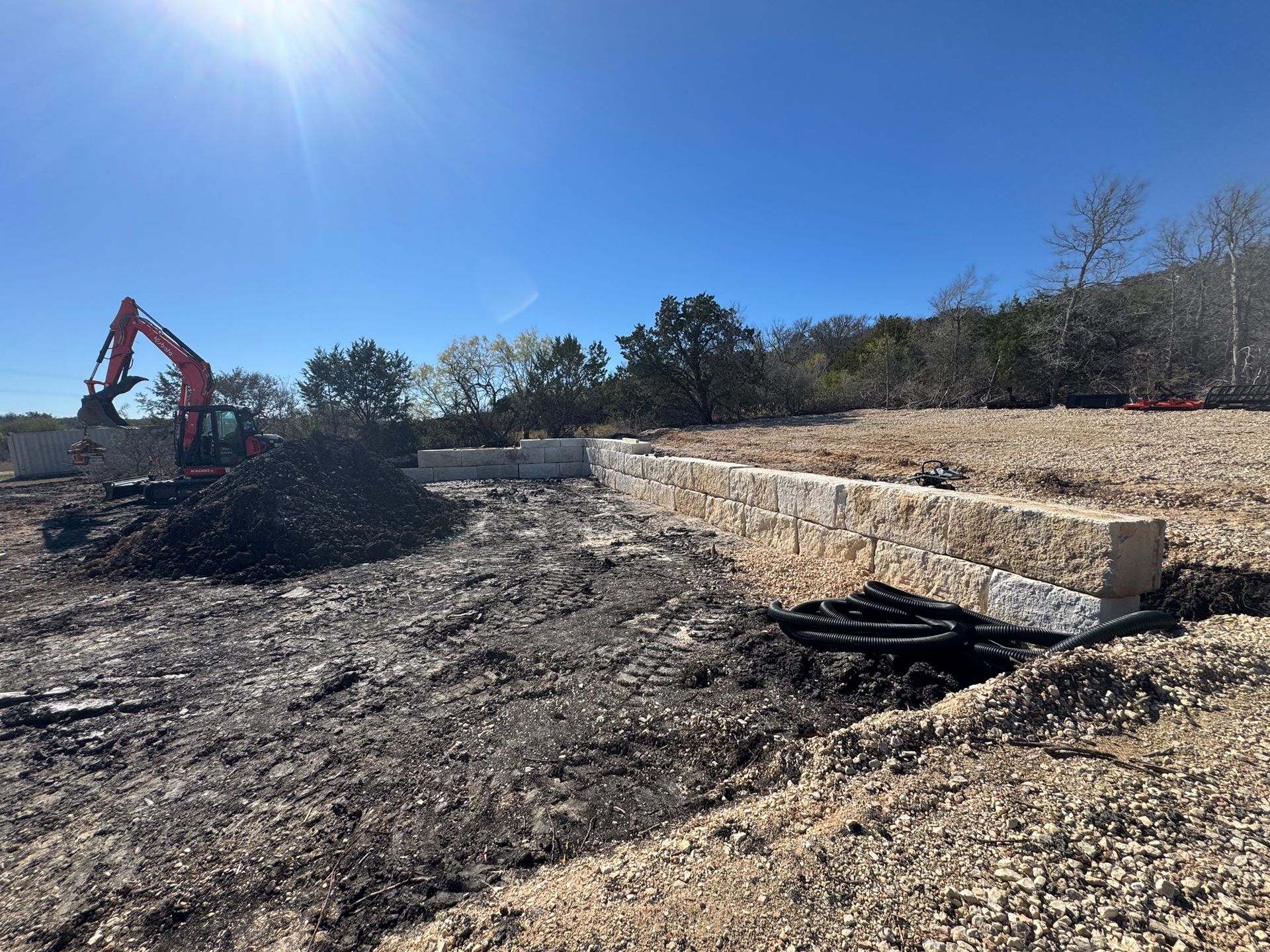 A large excavator is sitting in the middle of a dirt field.