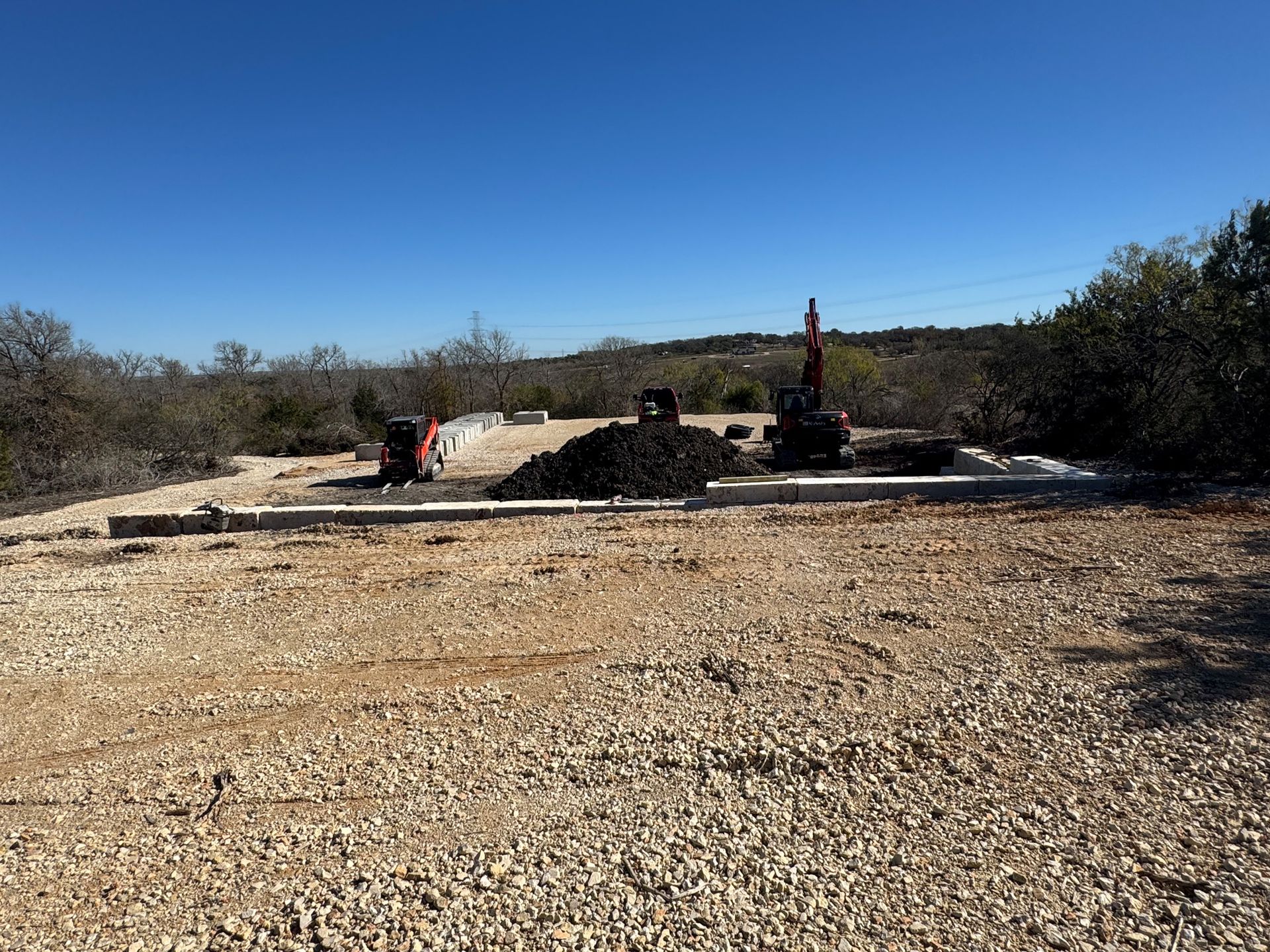 A large pile of gravel is sitting in the middle of a dirt field.