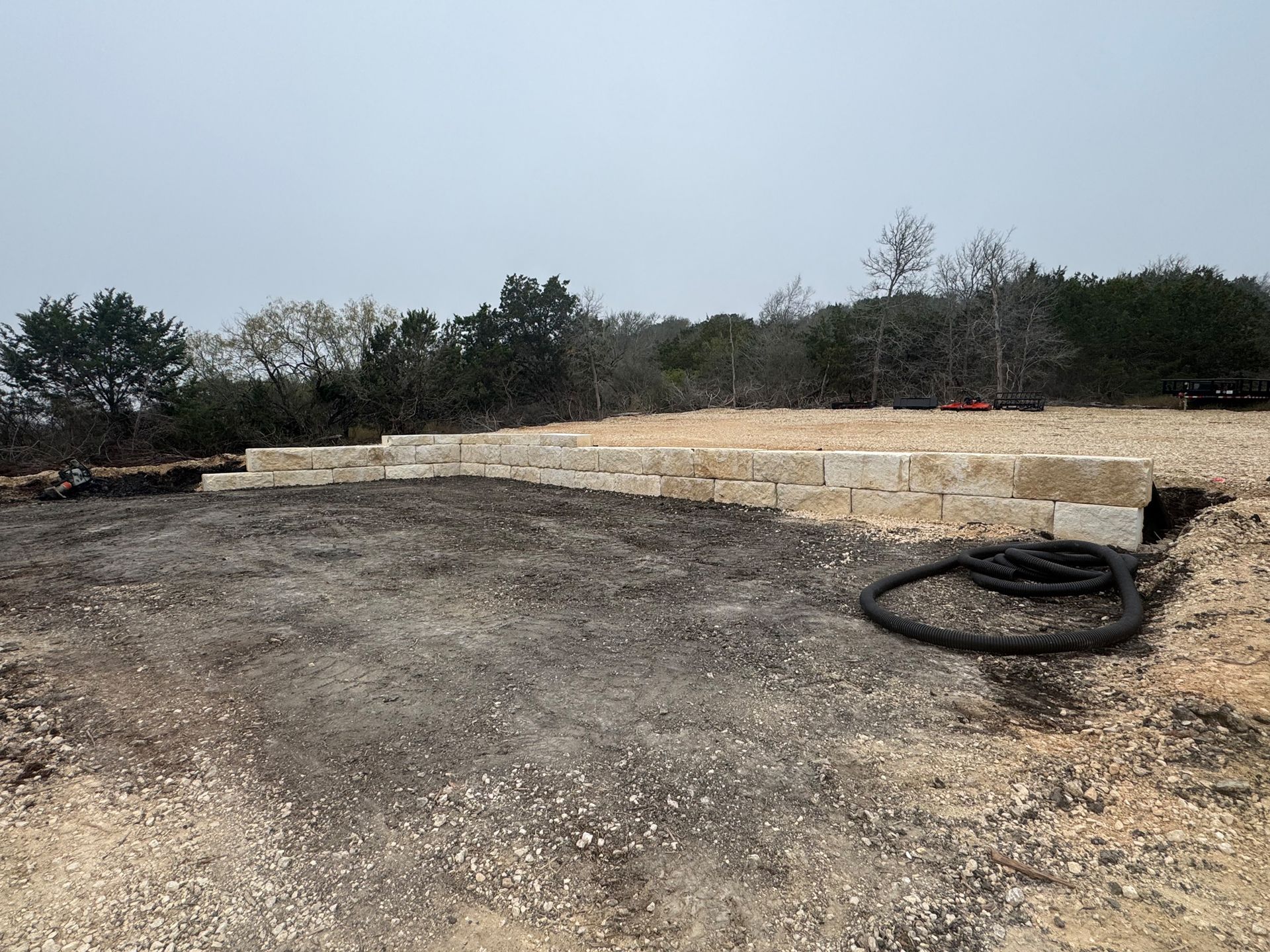 A large pile of dirt and rocks in a field with trees in the background.