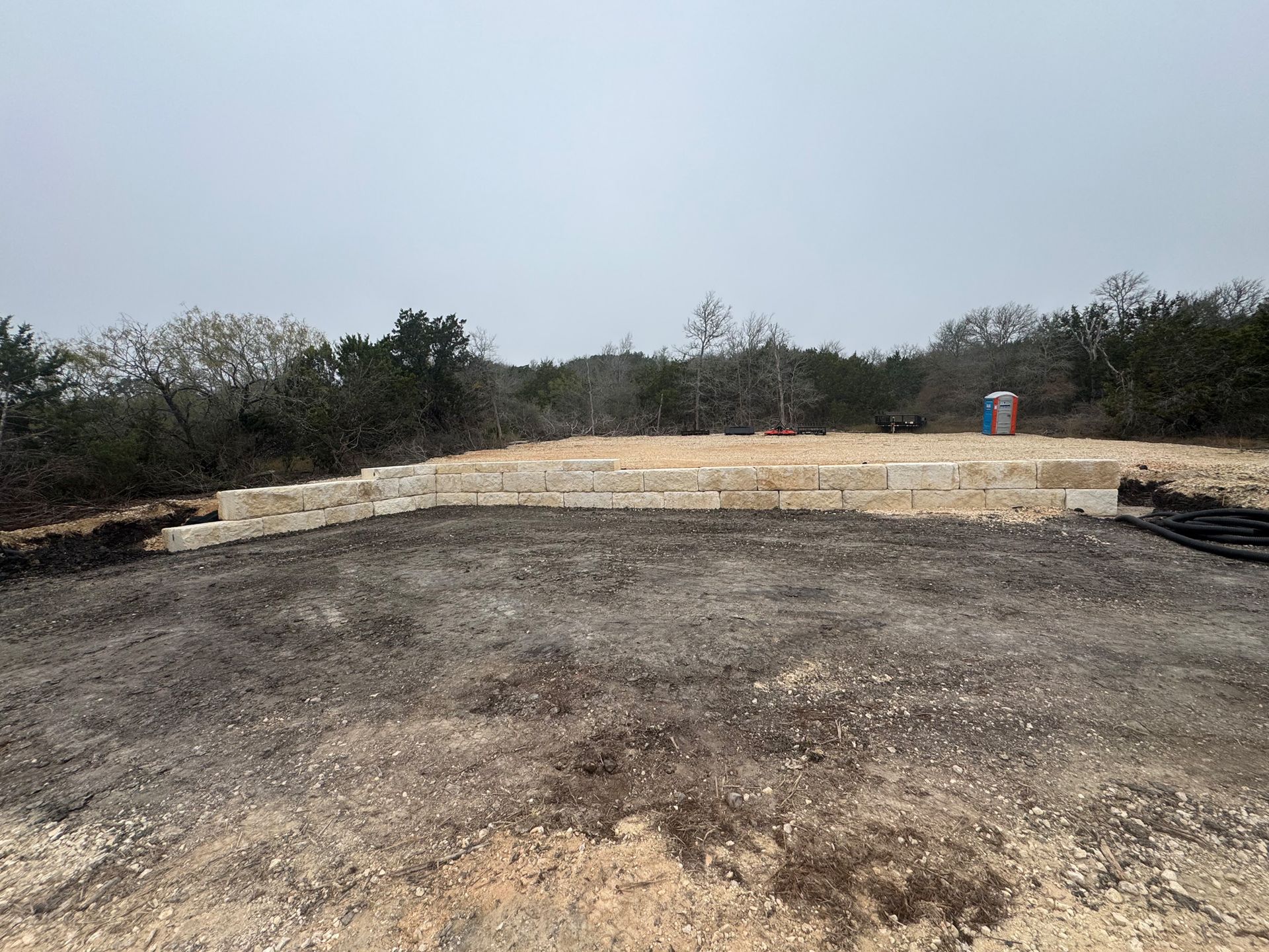 A large dirt field with a few trees in the background.