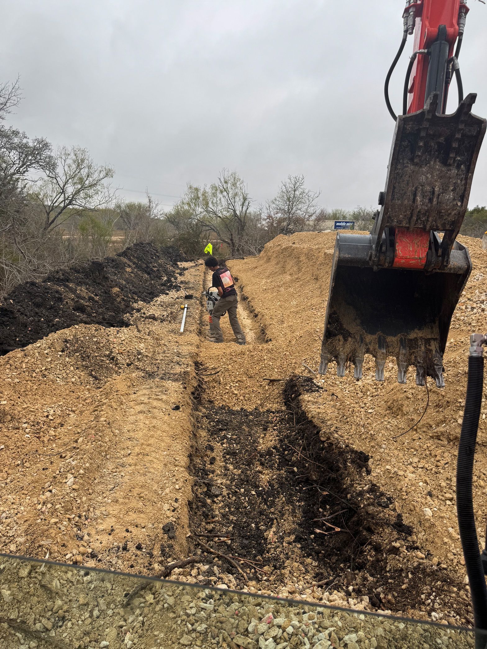 A man is digging in a pile of wood chips.
