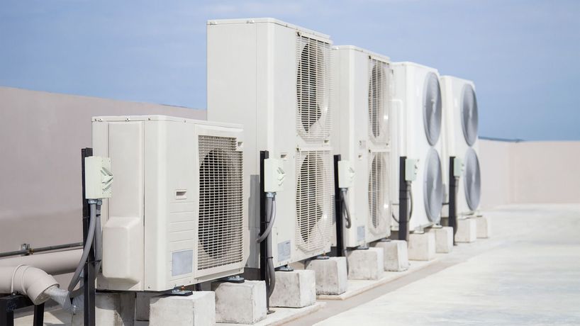 A row of air conditioners sitting on top of a building.