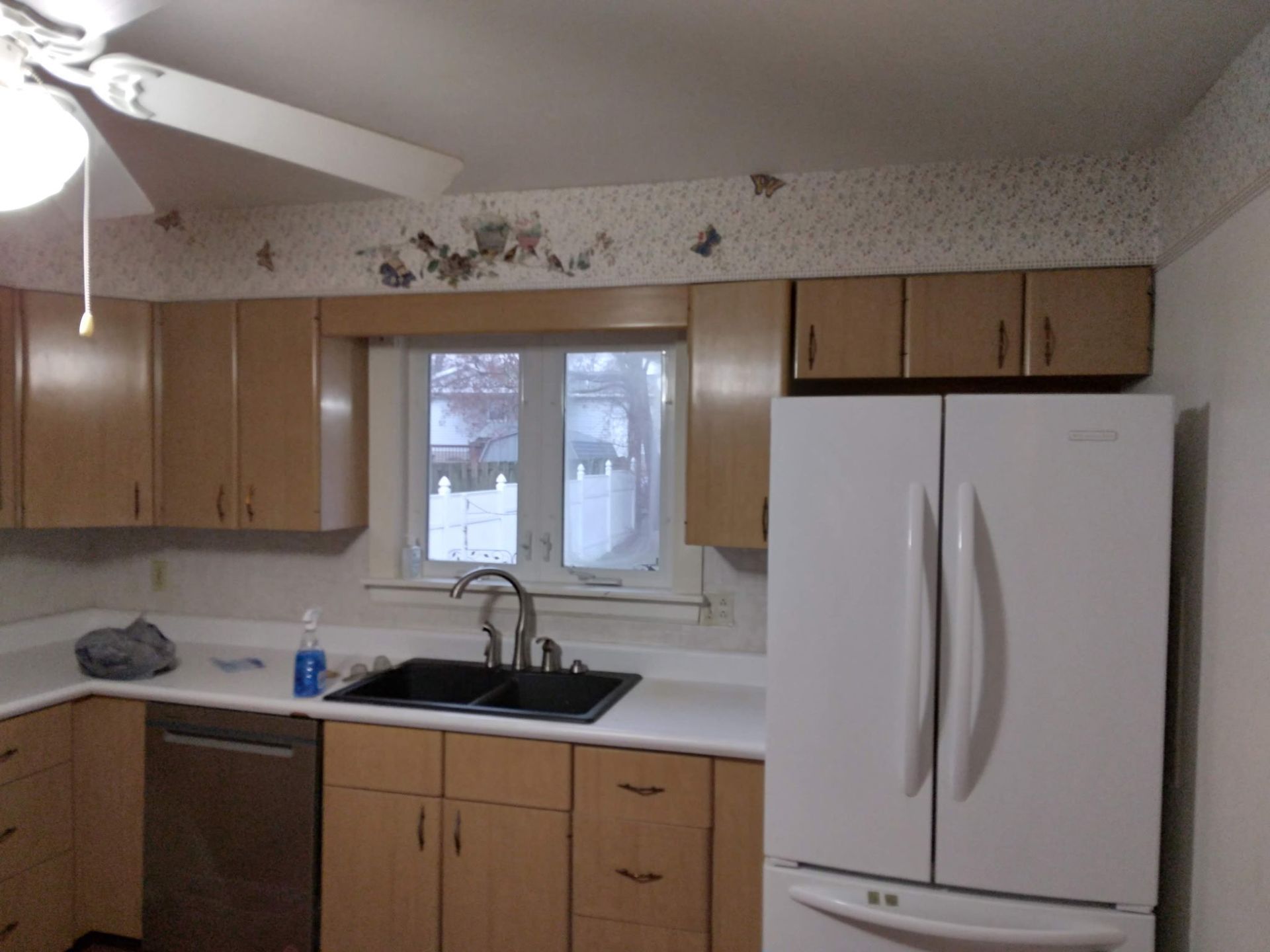 Kitchen with light wood cabinets, white countertops, and a white refrigerator.