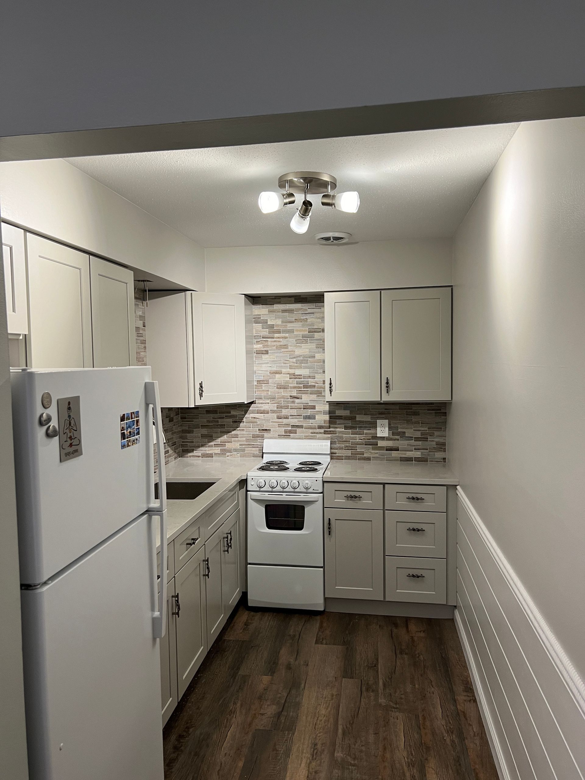 Modern bathroom with a white tub, herringbone wall, and gray accents; pendant lights.
