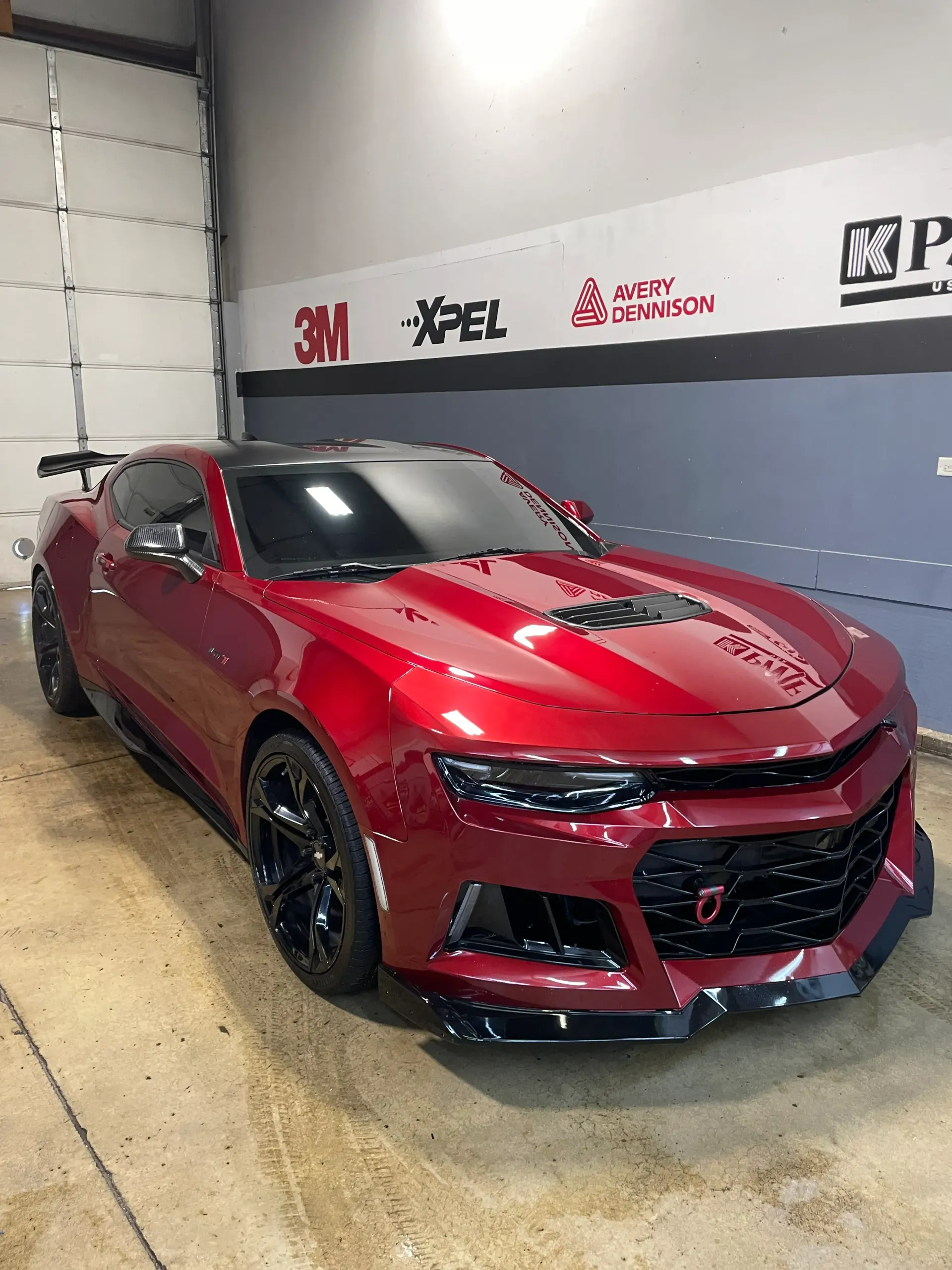 Blue Dodge Charger parked outside a building with its wheels and body covered in soap.