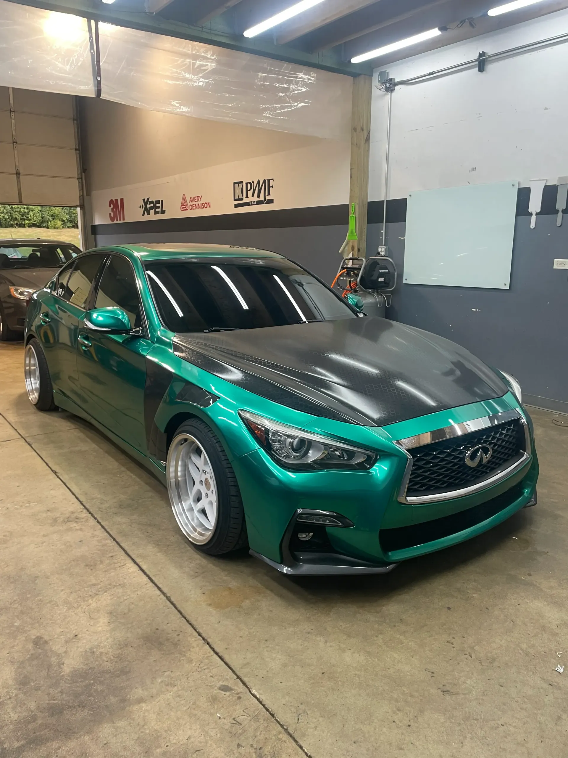 Bright blue Chevrolet Corvette convertible parked in front of a building with a white truck.