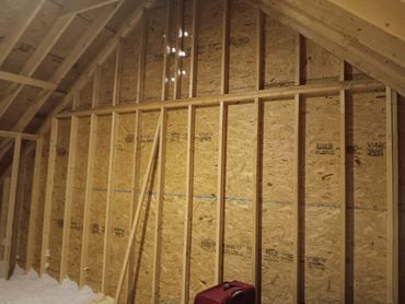 Interior framing of an attic space; wooden studs and OSB paneling.
