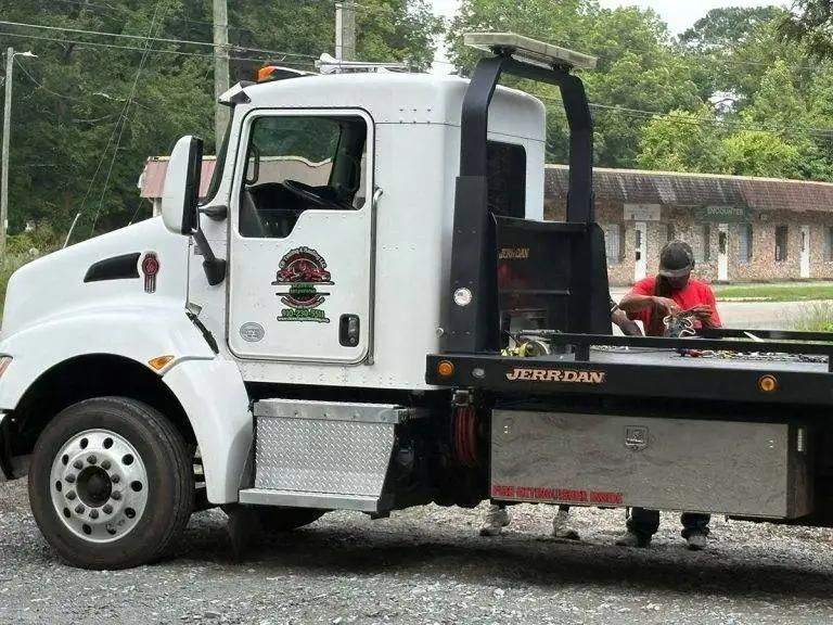 White tow truck with a driver, on a paved surface.