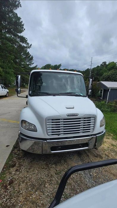 White Freightliner truck parked outdoors on a cloudy day.