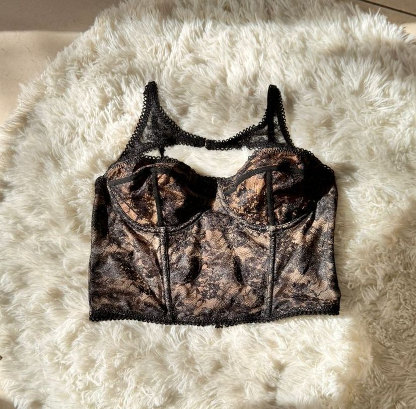 Bustier de encaje negro sobre una alfombra blanca esponjosa.