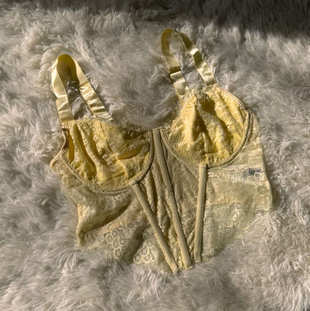 Top de corsé de encaje amarillo sobre alfombra blanca y esponjosa.