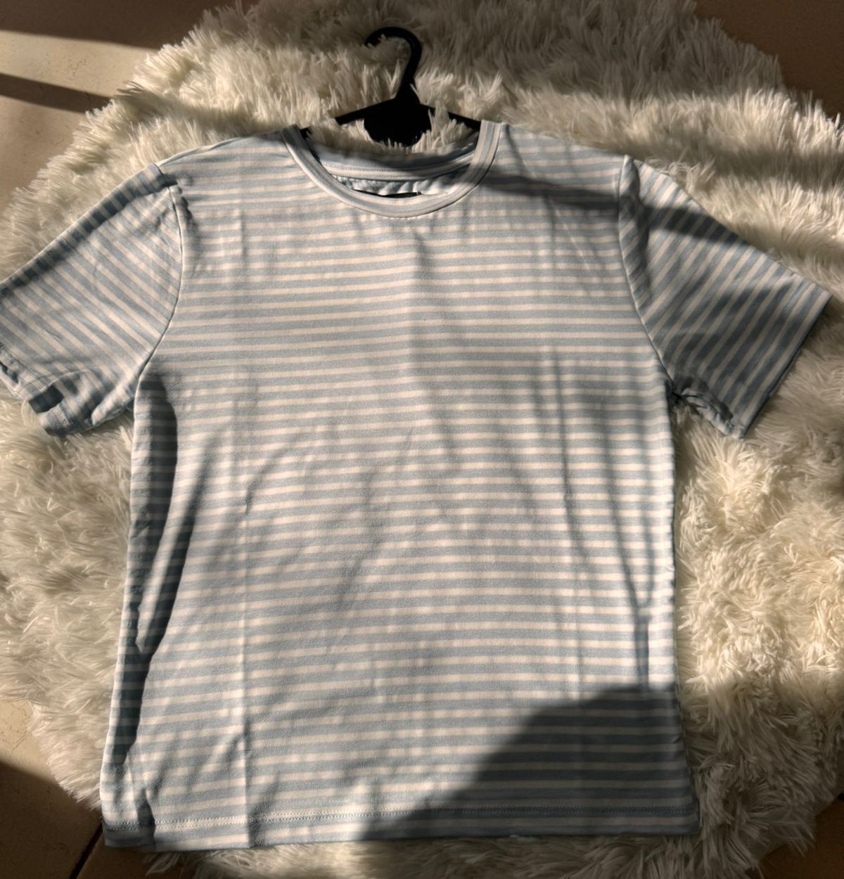 Camiseta de rayas celeste y blanca en una percha negra