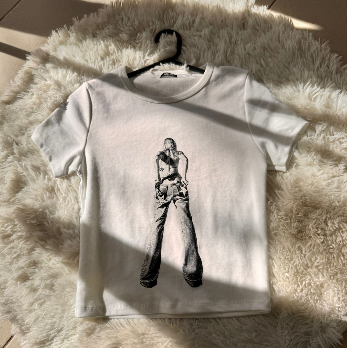 Camiseta blanca con dibujo negro de una persona con vaqueros
